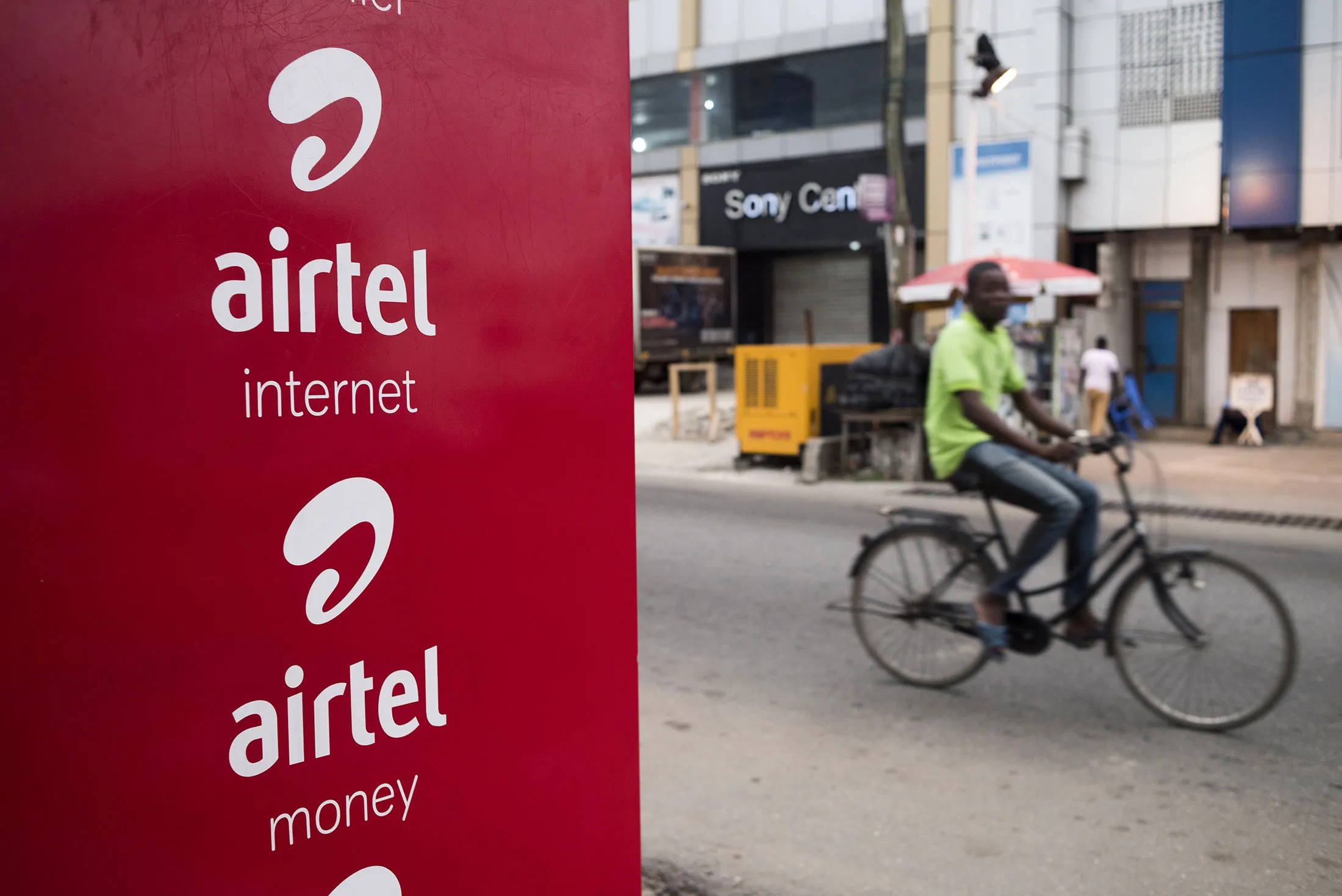 A man rides a bicycle past an advertisement for Airtel Ghana Ltd.
