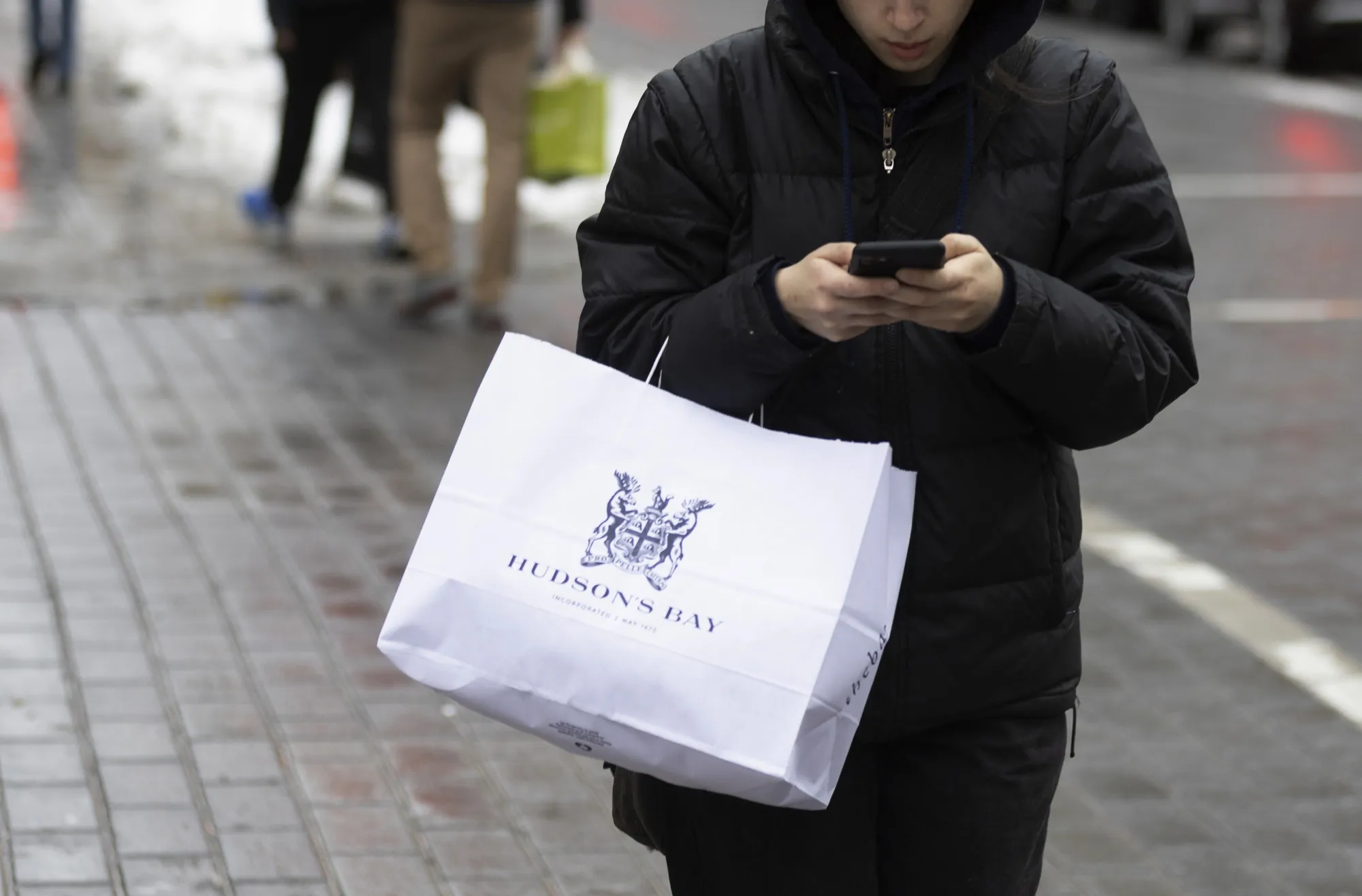 A shopper carries a Hudson's Bay bag.