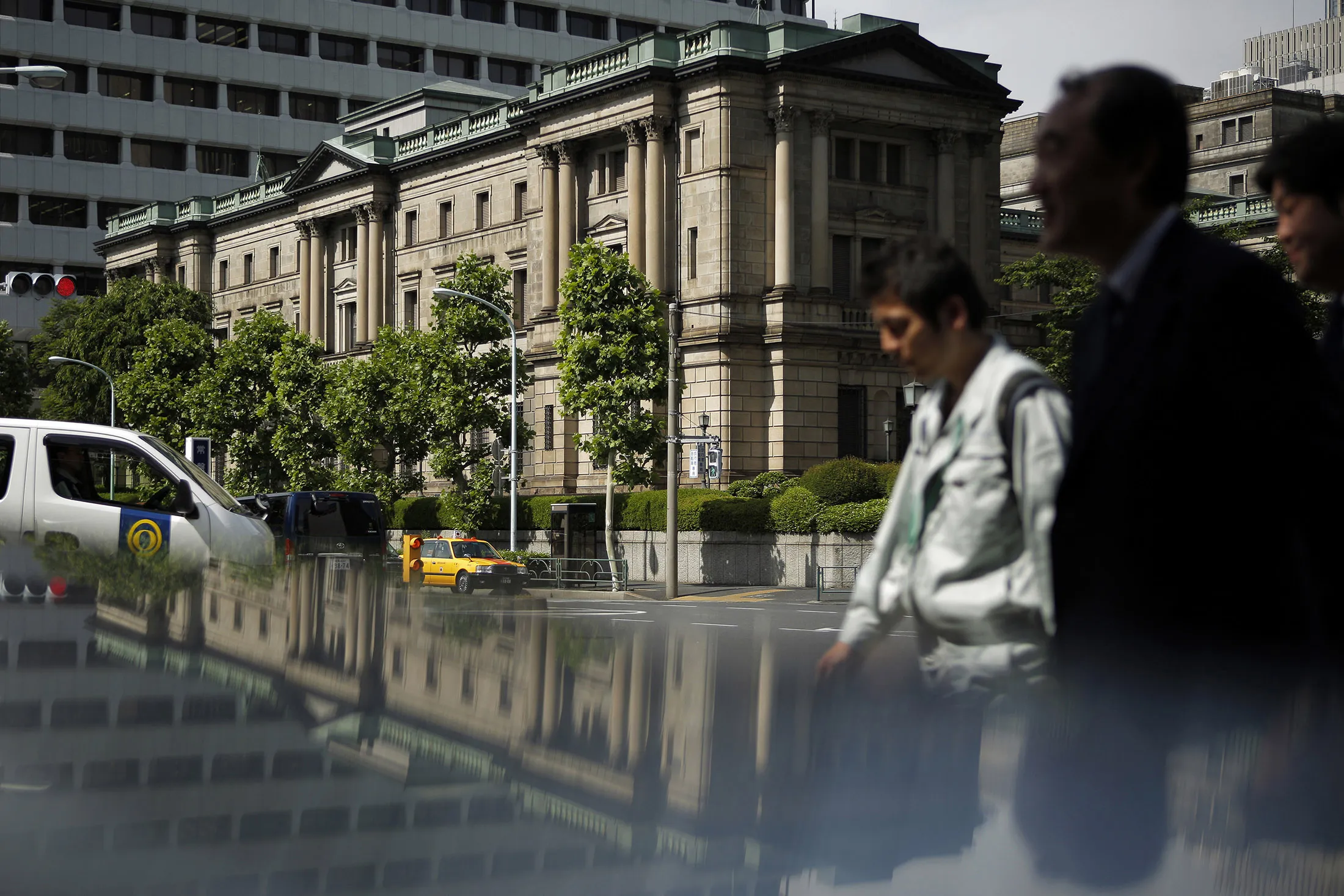 Pedestrians walk past the Bank of Japan headquarters in Tokyo.
