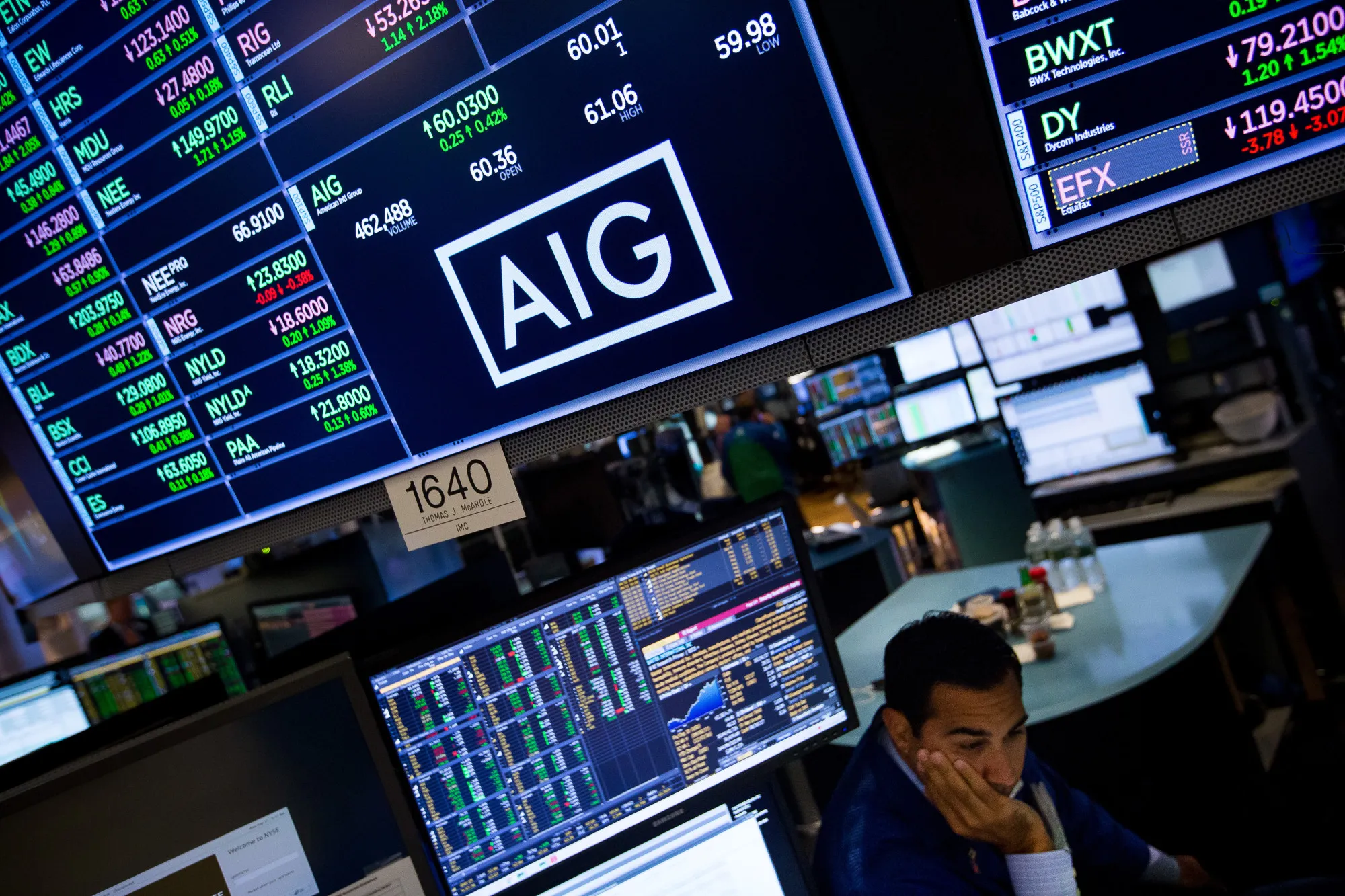 American International Group Inc. (AIG) signage above a trader on the floor of the New York Stock Exchange.