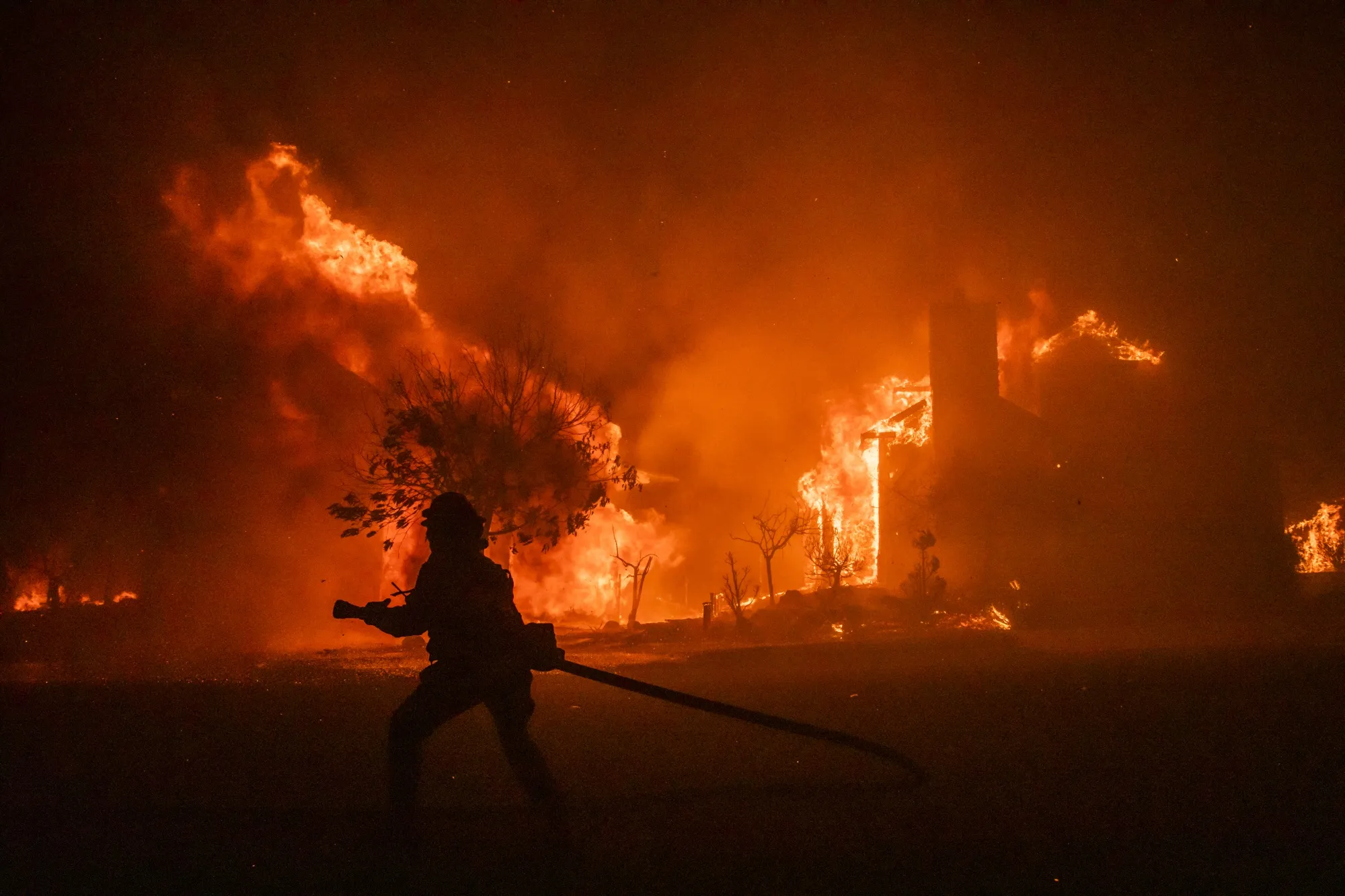 A firefighter carries a hose as buildings burn in the Skyhawk Park neighborhood of East Santa Rosa during the Shady Fire in Sonoma County, California, U.S., on&nbsp;Sept. 27.