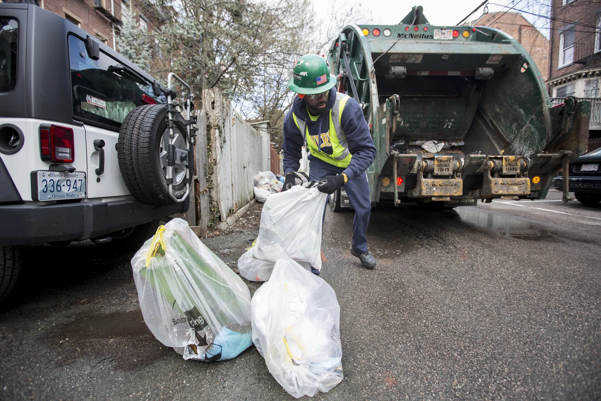 A trash collector moves bags of garbage during pickup in Boston.