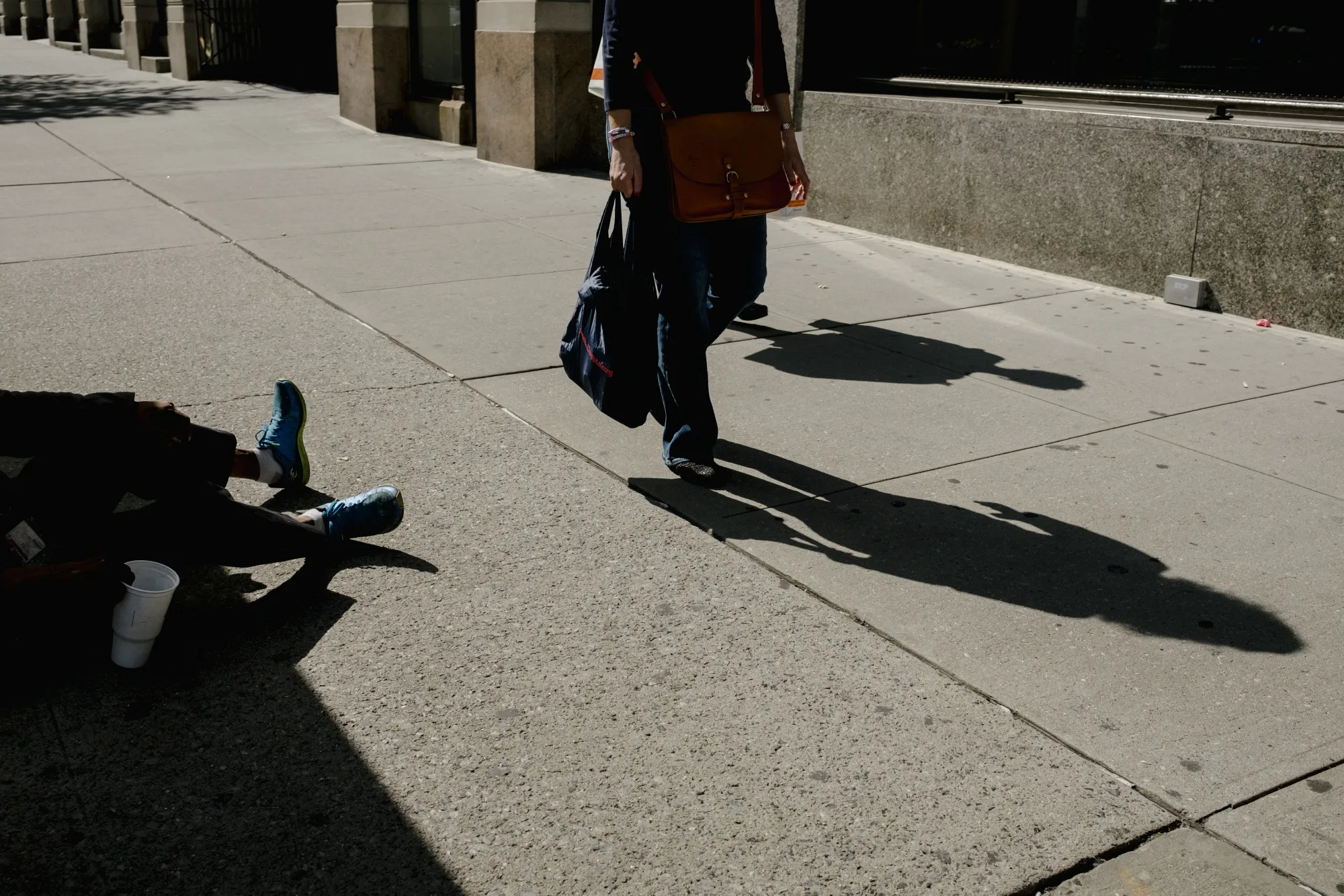 A person sitting on the street holds out a cup for money in&nbsp;New York.