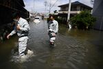 People wade through flood waters in Kurume, in Fukuoka Prefecture on July 8.