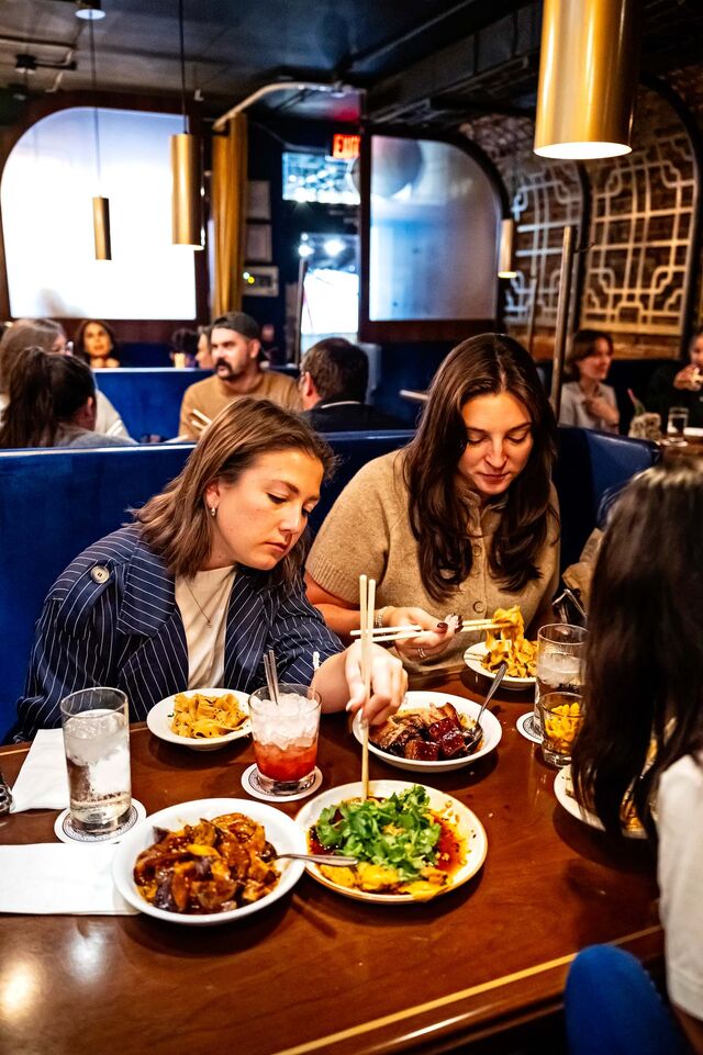 A group of people eating dumplings and noodles at Astoria restaurant.