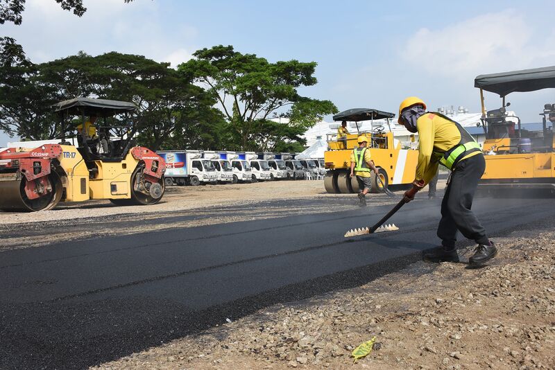 Workers lay a road made with asphalt and recycled plastics at a test site near Manila. Image: San Miguel Corp.