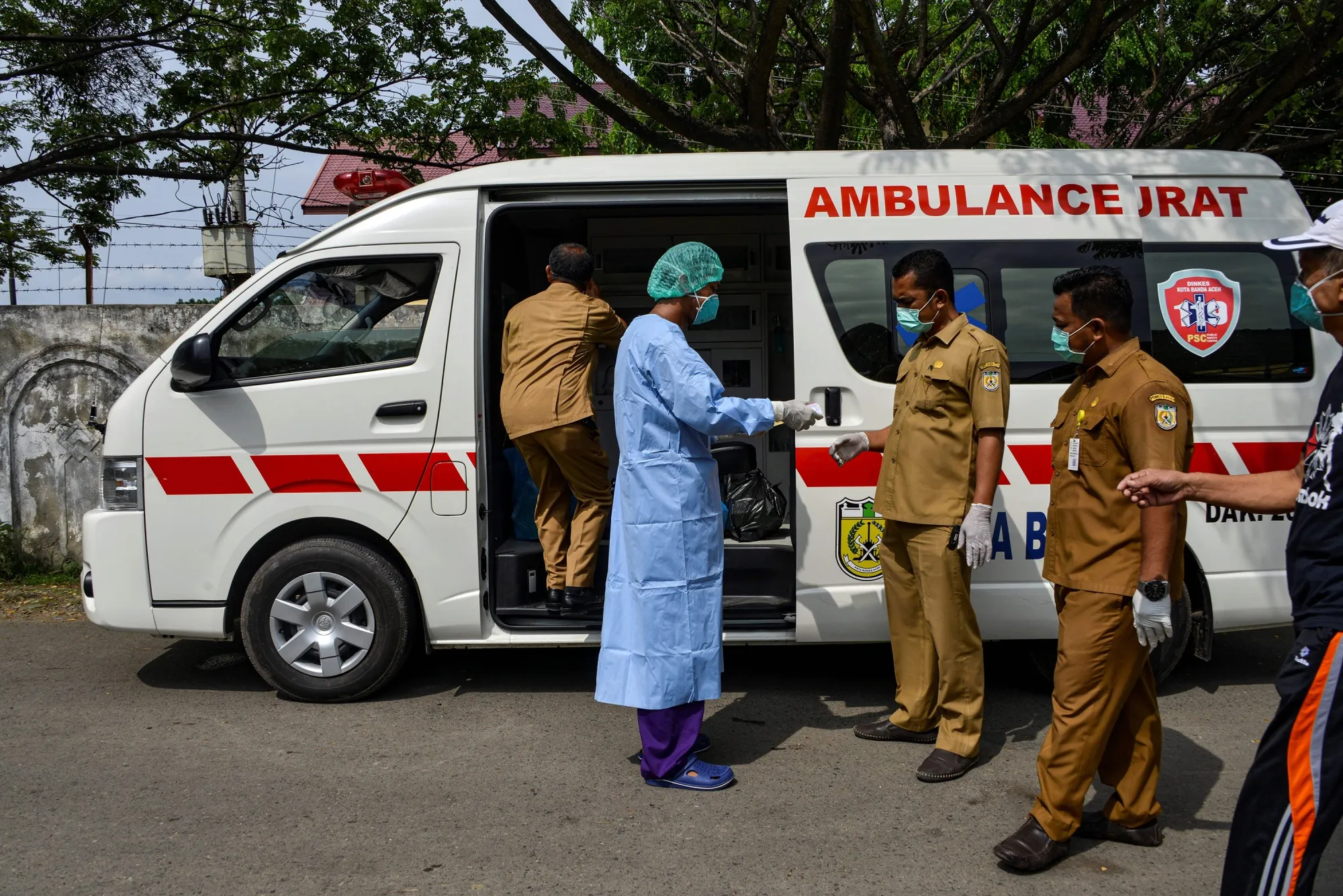 A medical worker and health officials prepare for a recovered coronavirus patient to be sent home via ambulance from the Zainoel Abidin hospital in Banda Aceh on April 13.