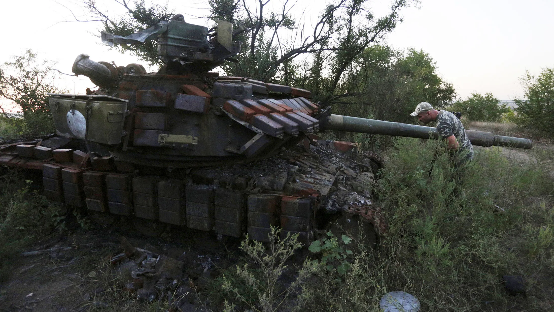 A serviceman next to a destroyed tank on the position of Ukrainian forces in the Lugansk region on August 26, 2015.

