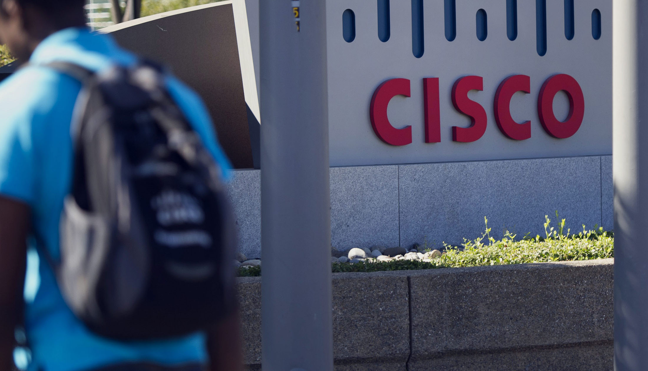 A pedestrian walks past Cisco Systems Inc. signage at the company’s headquarters in San Jose, California.
