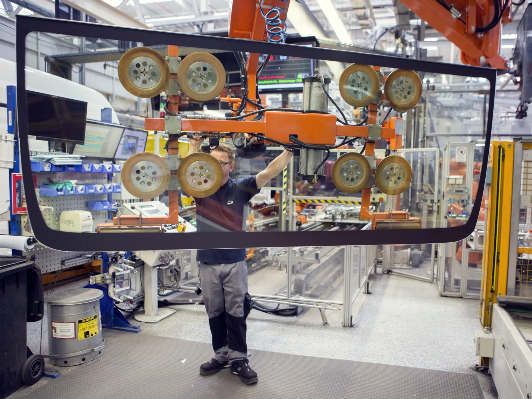 An employee uses a suction winch to move a windshield inside the MAN SE factory in Munich.