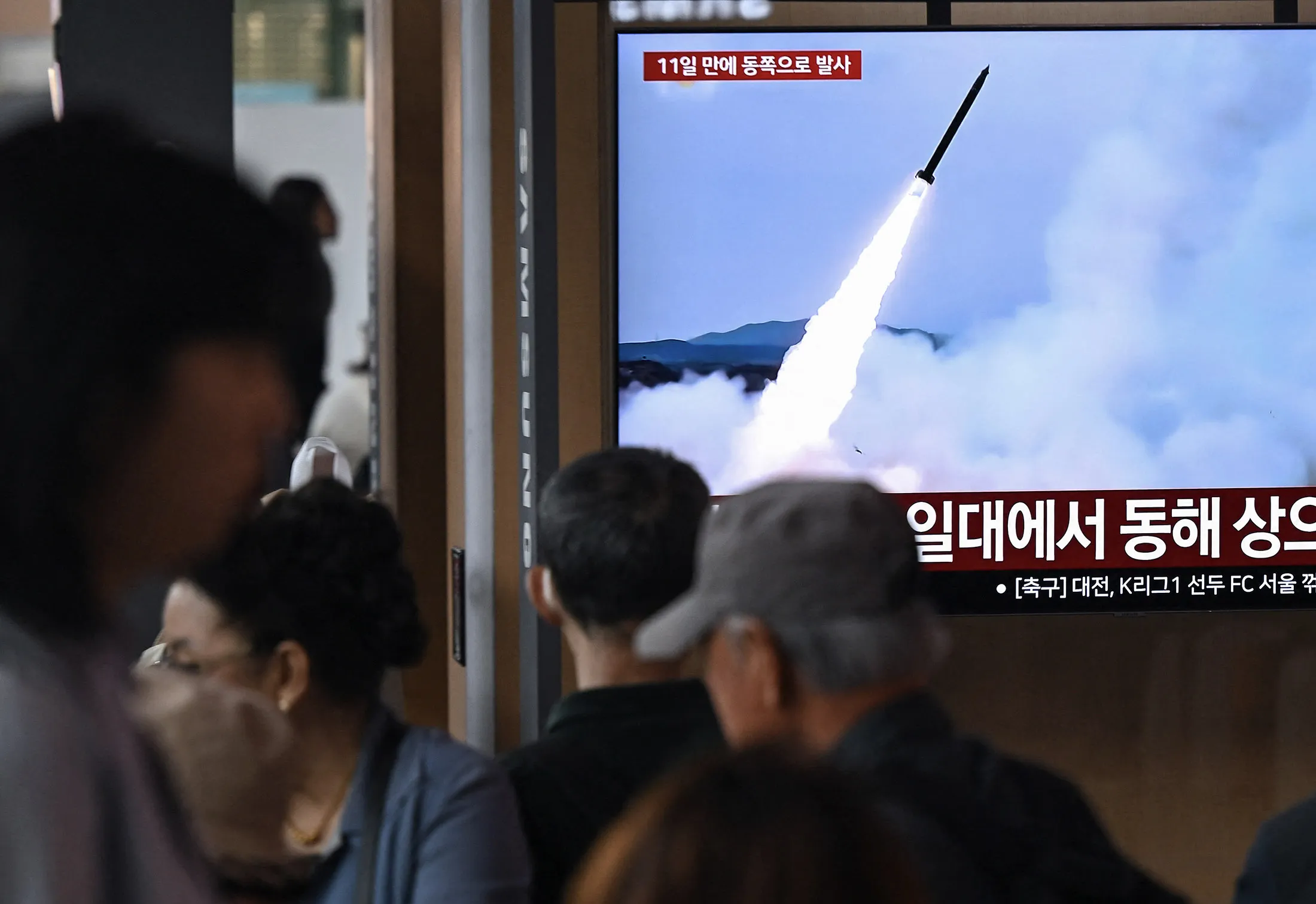 A news broadcast showing file footage of a North Korean missile test, at a train station in Seoul.