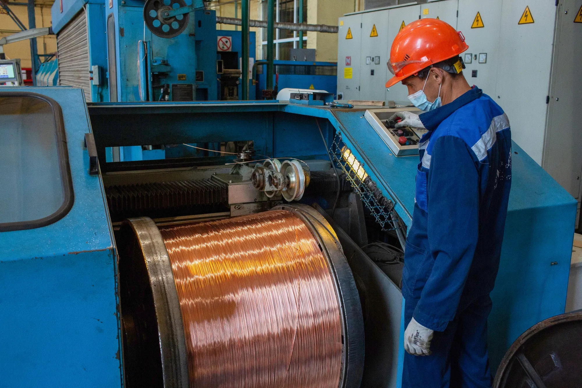 A worker monitors a machine as it spools copper wire rod following manufacture at the Uralelectromed Copper Refinery, operated by Ural Mining and Metallurgical Co., in Verkhnyaya Pyshma, Russia.