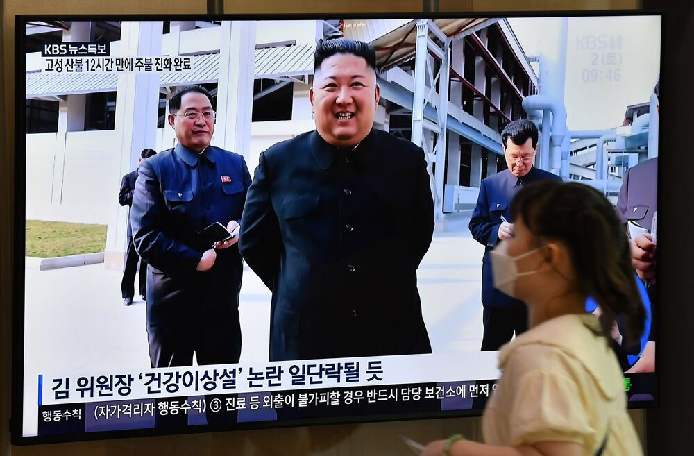 A woman walks past a television news screen showing a picture of North Korean leader Kim Jong Un attending a ceremony to mark the completion of Sunchon phosphatic fertiliser factory, at a railway station in Seoul.