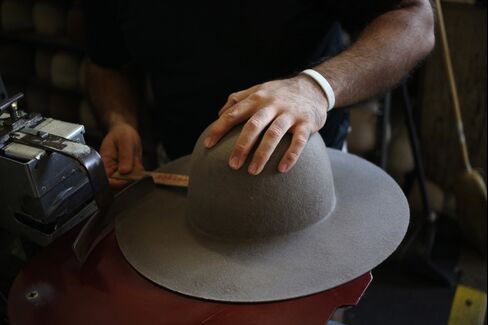 A worker uses her hands to help sand and smooth a Stetson brand cowboy hat during production at the Hatco Inc. manufacturing facility in Garland, Texas, U.S.