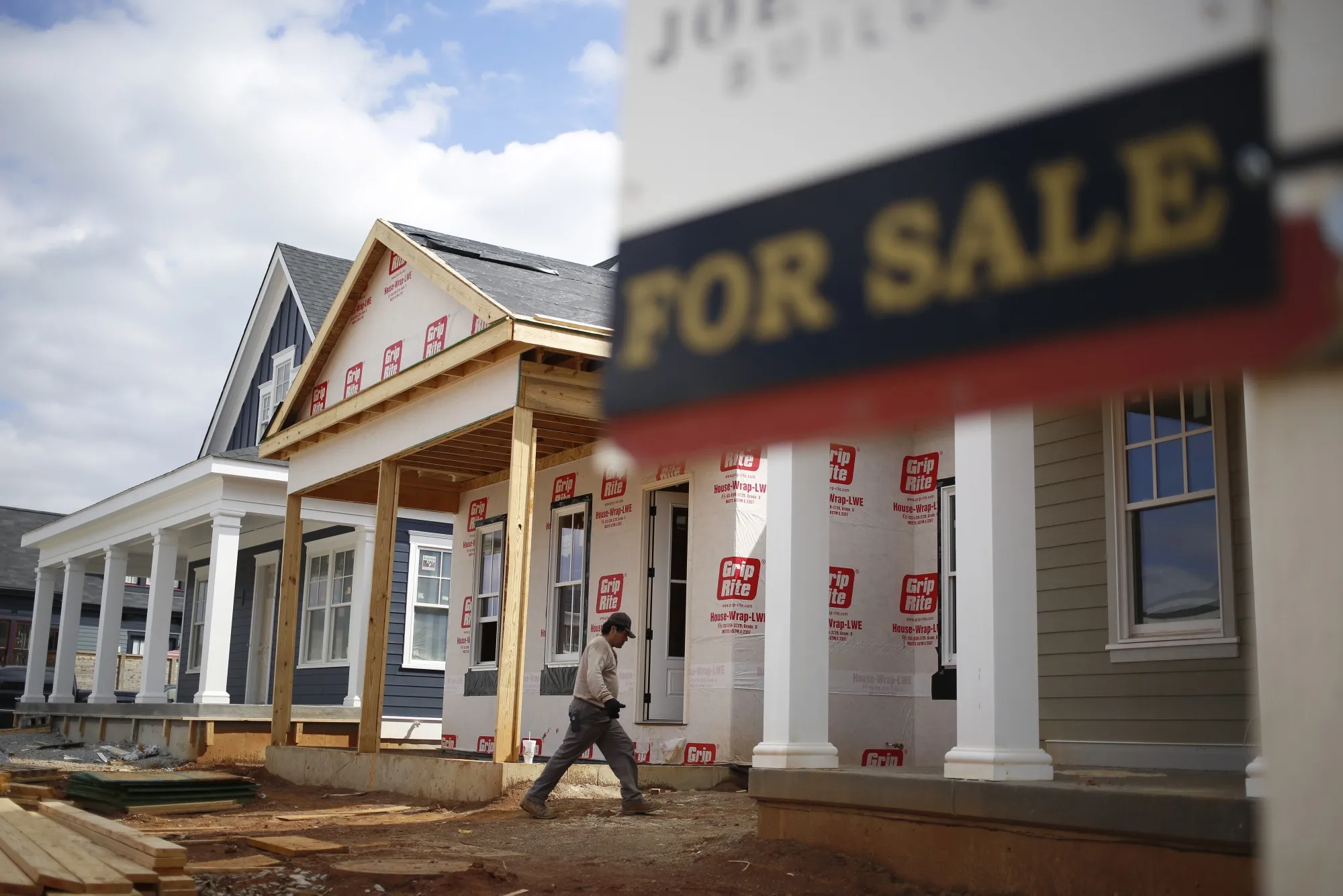 A contractor walks past a "For Sale" sign in Louisville, Kentucky.