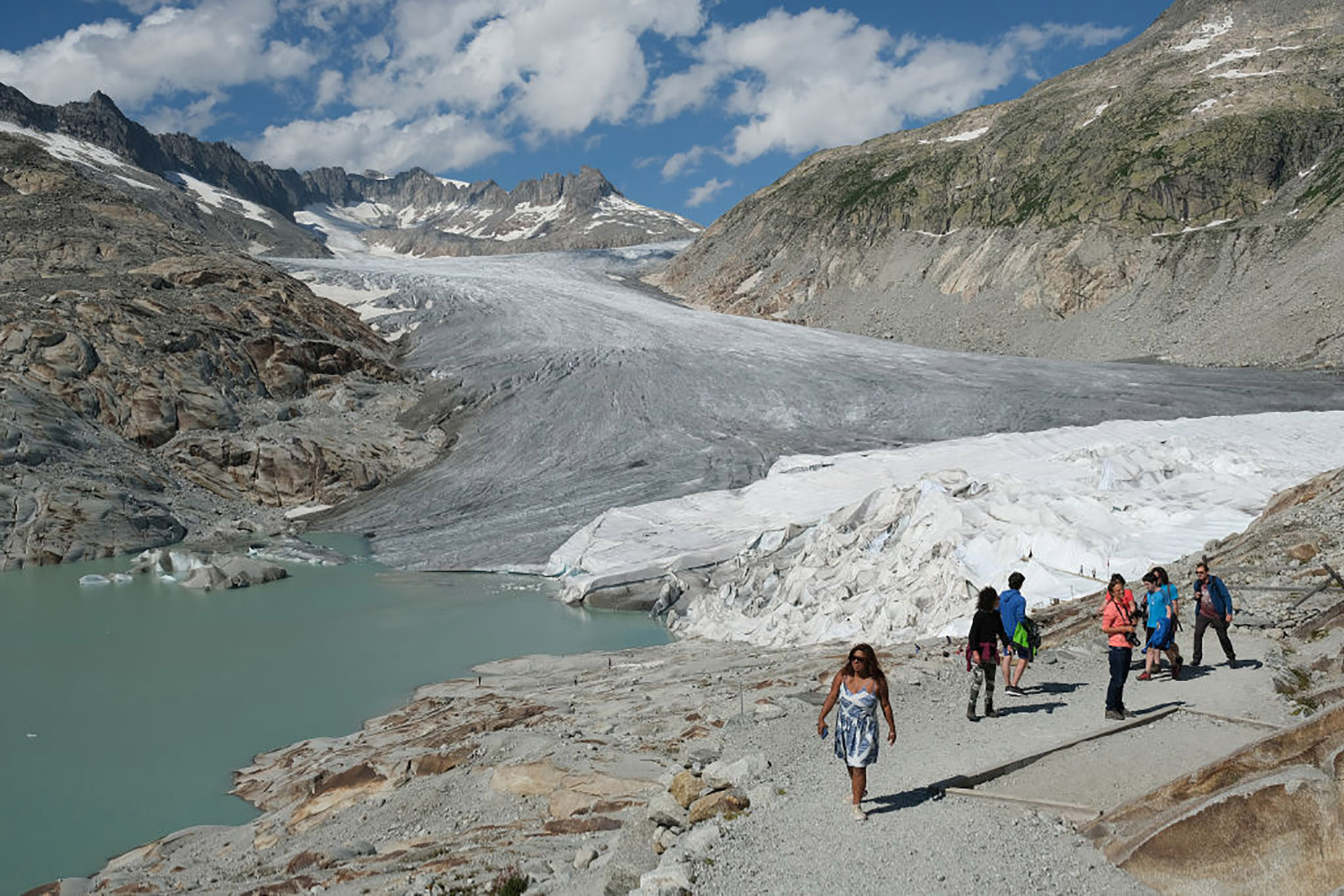 The Rhone glacier above a lake formed by the glacier's meltwater as well as a portion of the glacier covered in UV-resistant material to slow the glacier's melting.
