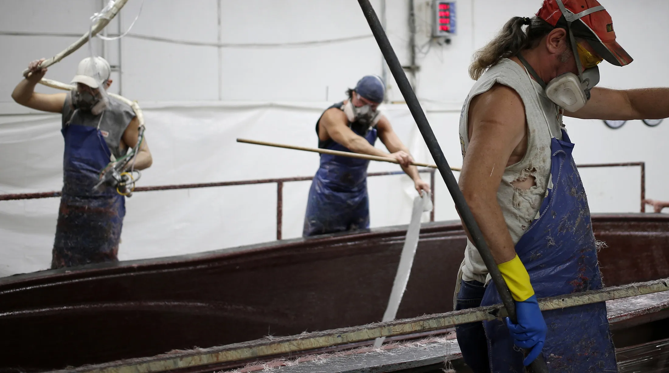 Workers apply fiberglass to an inboard speed boat mold at a factory in Vonore, Tennessee.
