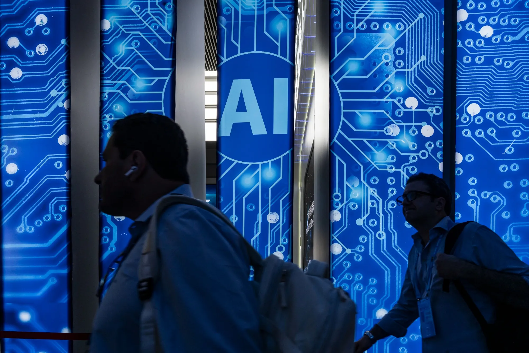 Attendees walk past artificial intelligence (AI) signage at the Canton Fair in Guangzhou, China.