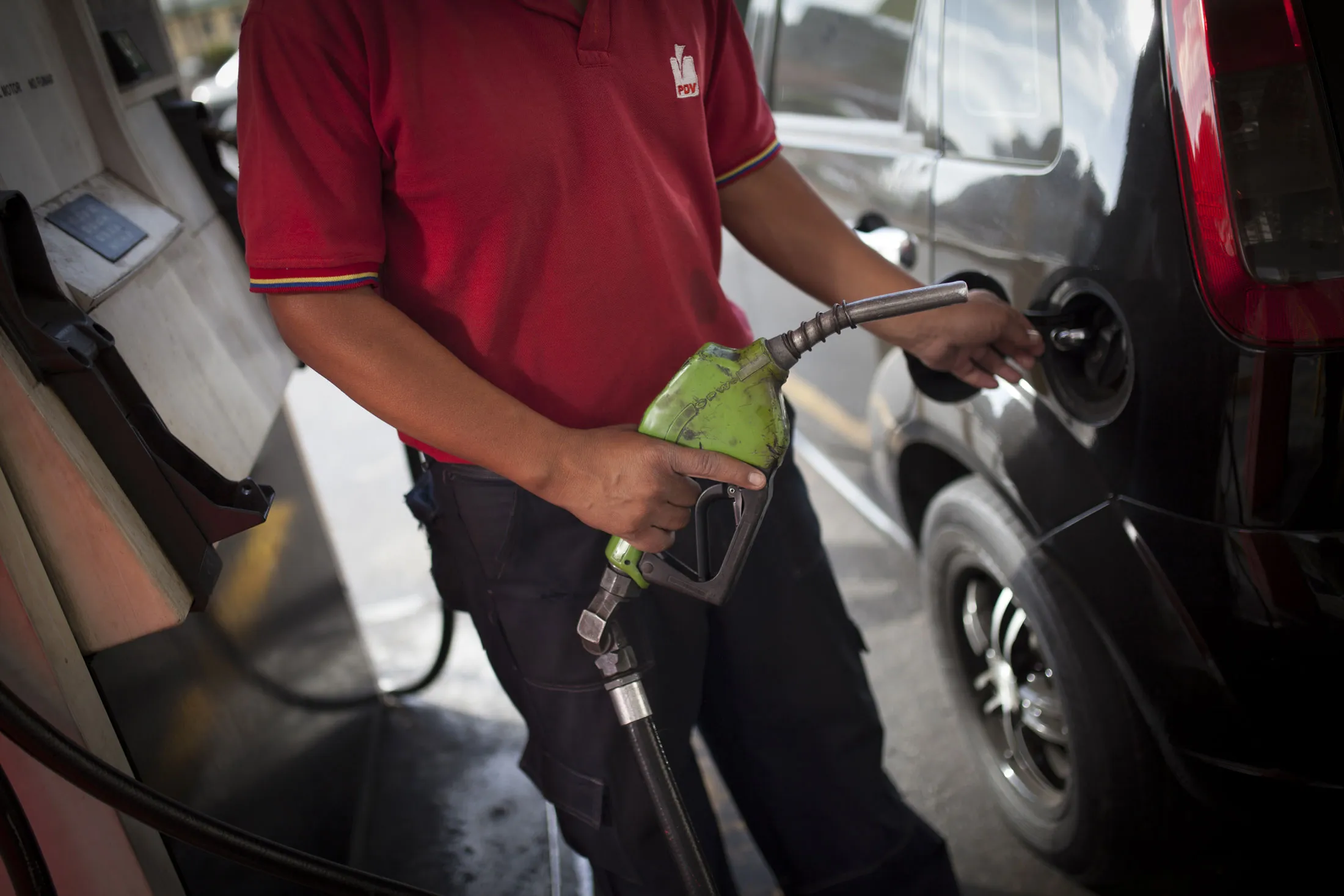 An attendant uses a handpump to refuel a vehicle in a Petroleos de Venzuela SA gas (PDVSA) station
