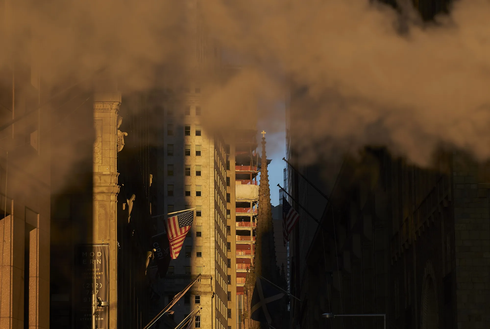 Steam rises above an American flag flying near the New York Stock Exchange.