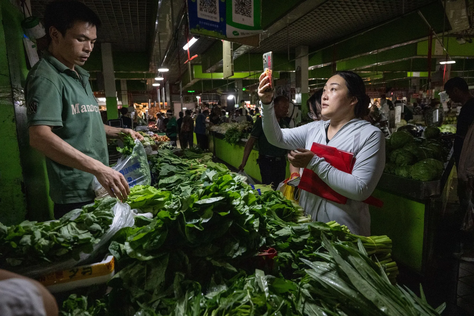 A customer scans a QR code to purchase vegetables at a wet market in Beijing.