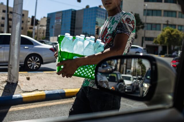 A teenage boy sells bottles of cold water to motorists at a junction in Amman, Jordan.