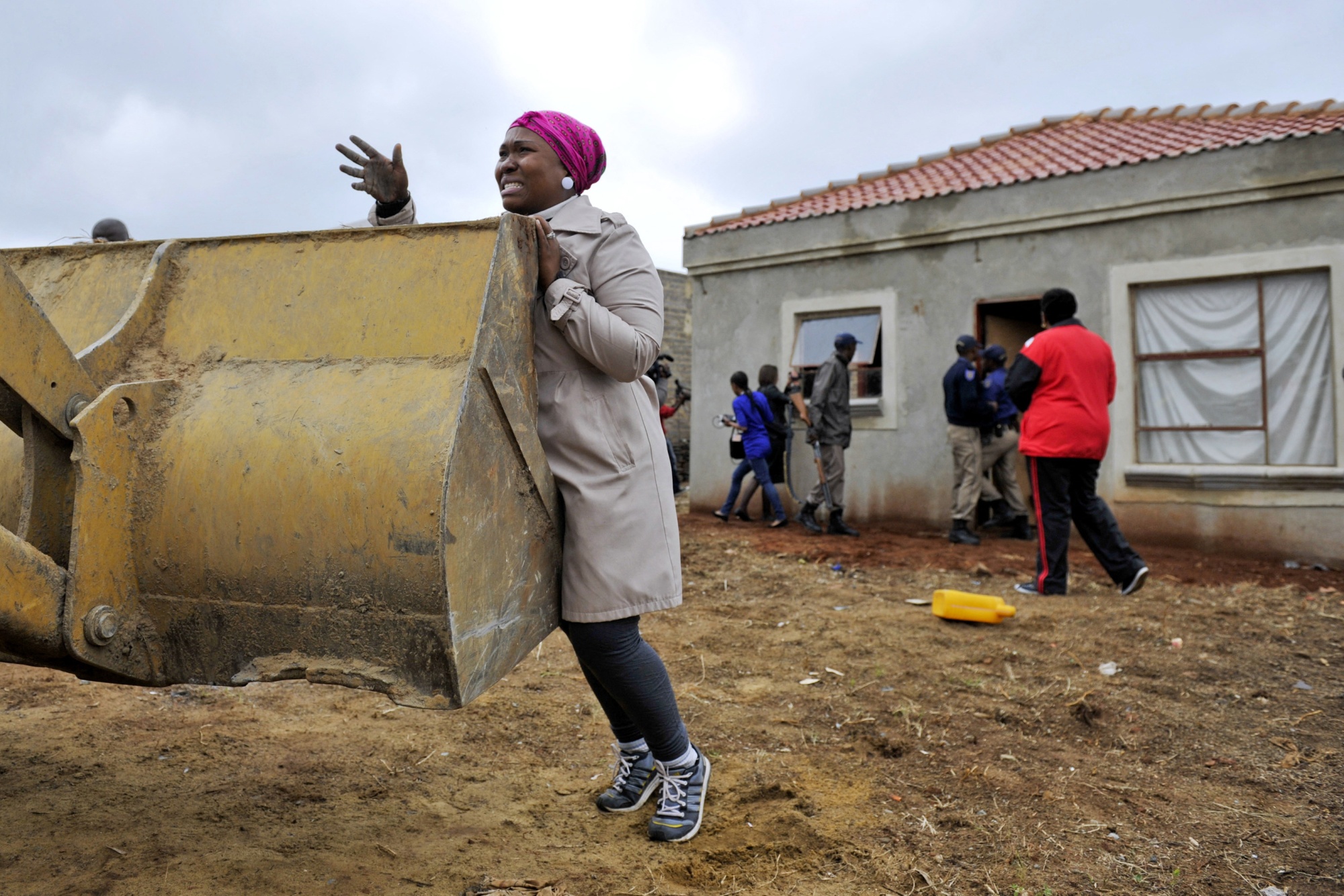 A woman tries to stop a bulldozer from destroying her house in Lenesia, southwest of Johannesburg, in November 2012. Earlier that day, protests erupted after the government demolished 37 homes.