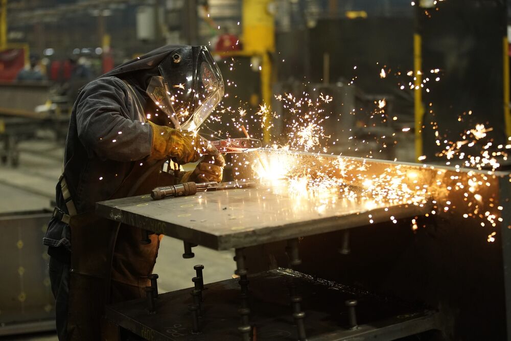A worker welds a structural steel beam during production at a steel facility in West Jordan, Utah.