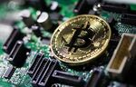 A coin representing Bitcoin cryptocurrency sits on a computer circuit board in this arranged photograph in London, U.K.
