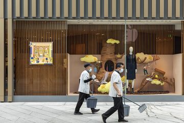 Cleaners walk past a luxury goods store at an upscale retail area in Beijing, China.