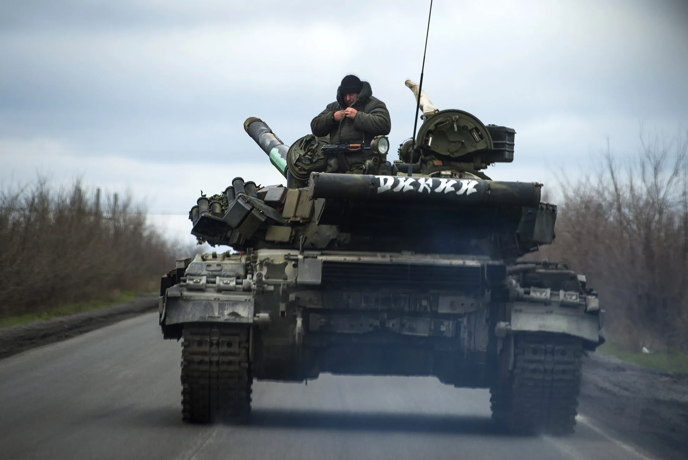 Pro-Russian separatist soldiers stand on their tank as they drive along a road near the village of Kirovske, in the self-proclaimed Donetsk People's Republic.
