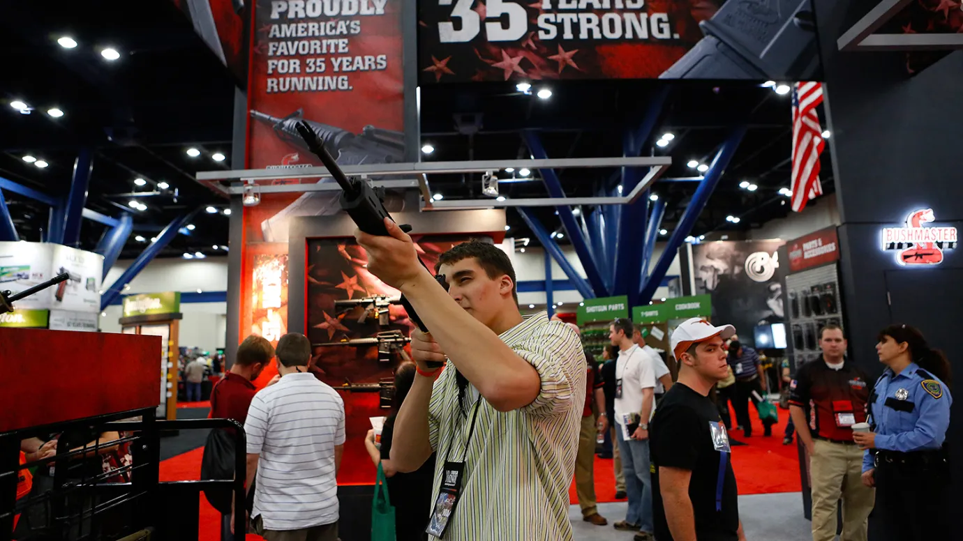 An attendee looks through the scope of a Freedom Group Inc. Bushmaster rifle during the 2013 National Rifle Association (NRA) Annual Meetings &amp; Exhibits at the George R. Brown Convention Center in Houston, Texas, on May 4, 2013.
