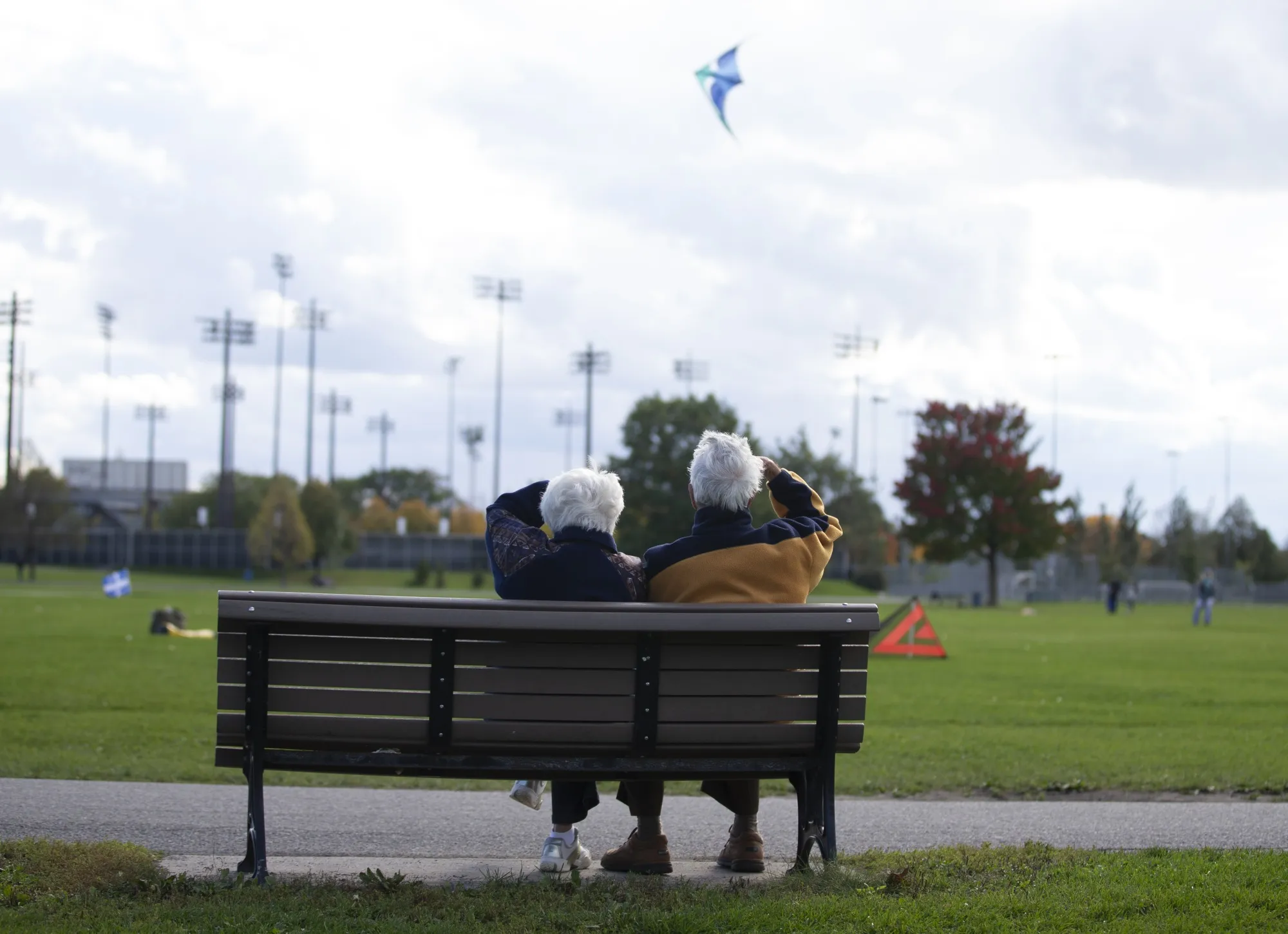 People sit on a bench in a park in Montreal.
