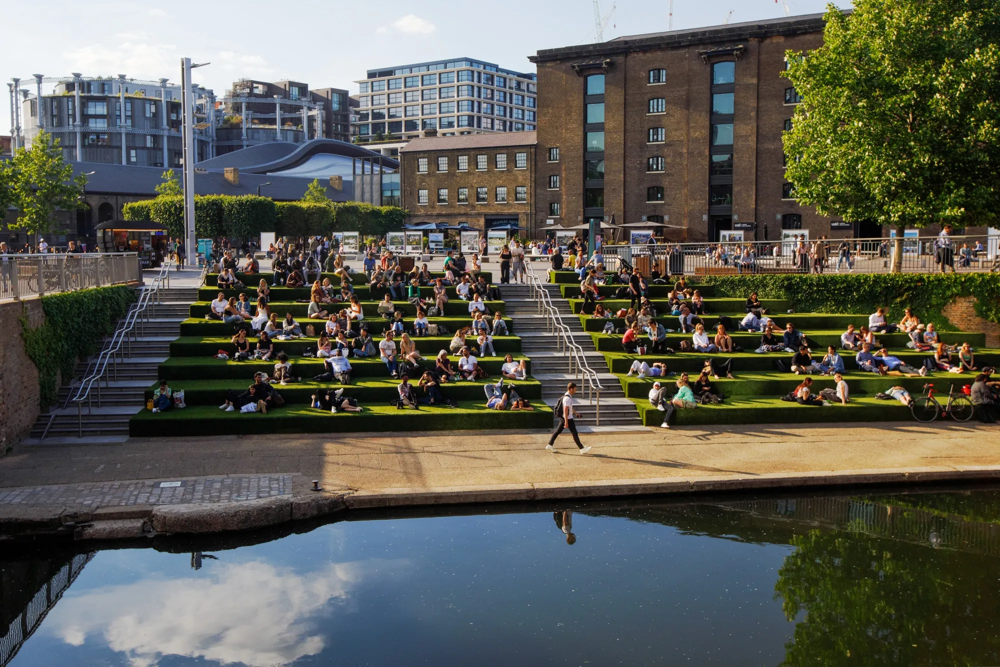 People sit on a terrace next to the London Canal near Granary Square and the University of the Arts London's Central Saint Martins college campus.
