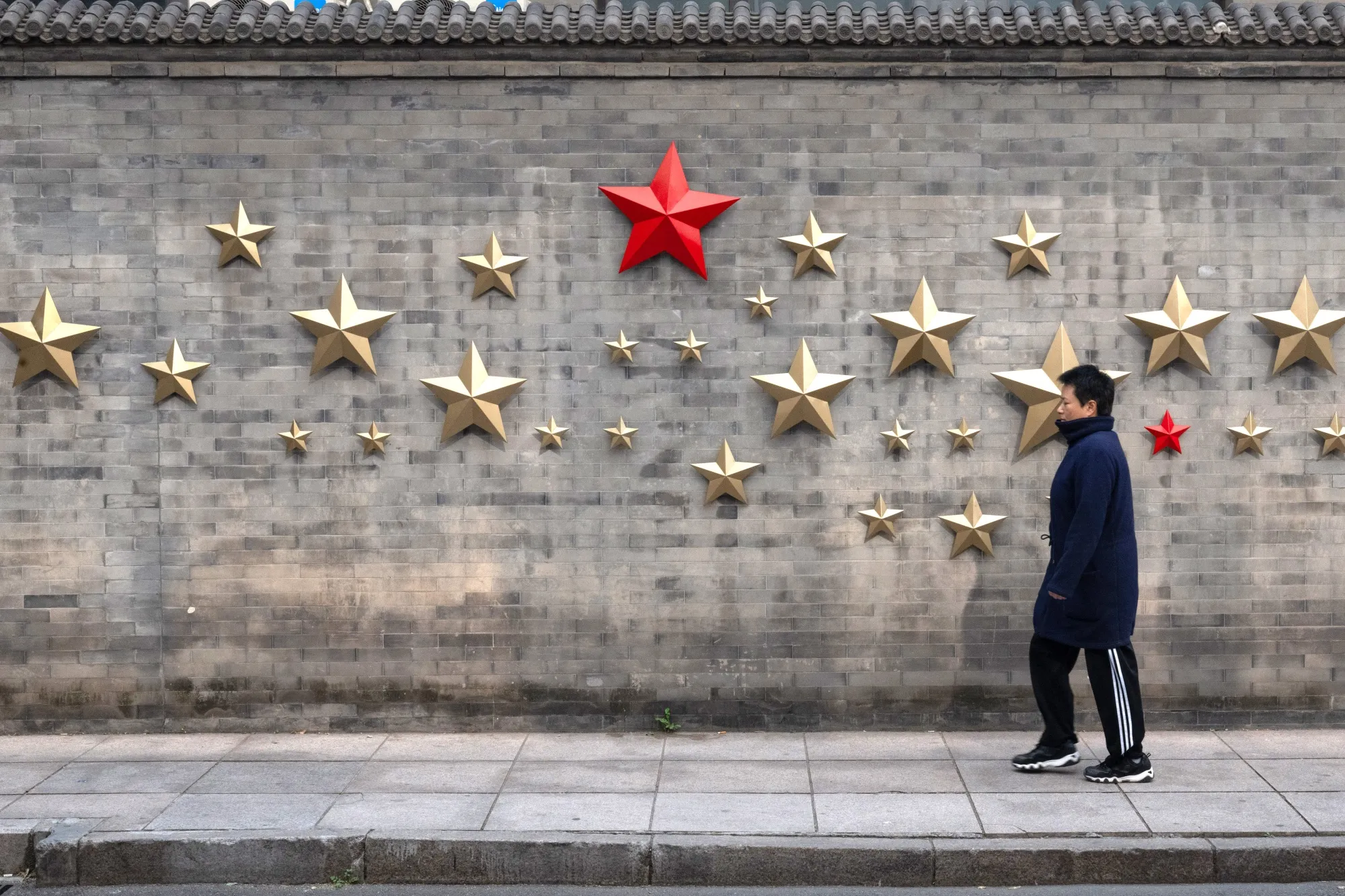 A pedestrian passes red stars on a wall in Beijing, China, on Friday, Nov. 8, 2024.&nbsp;