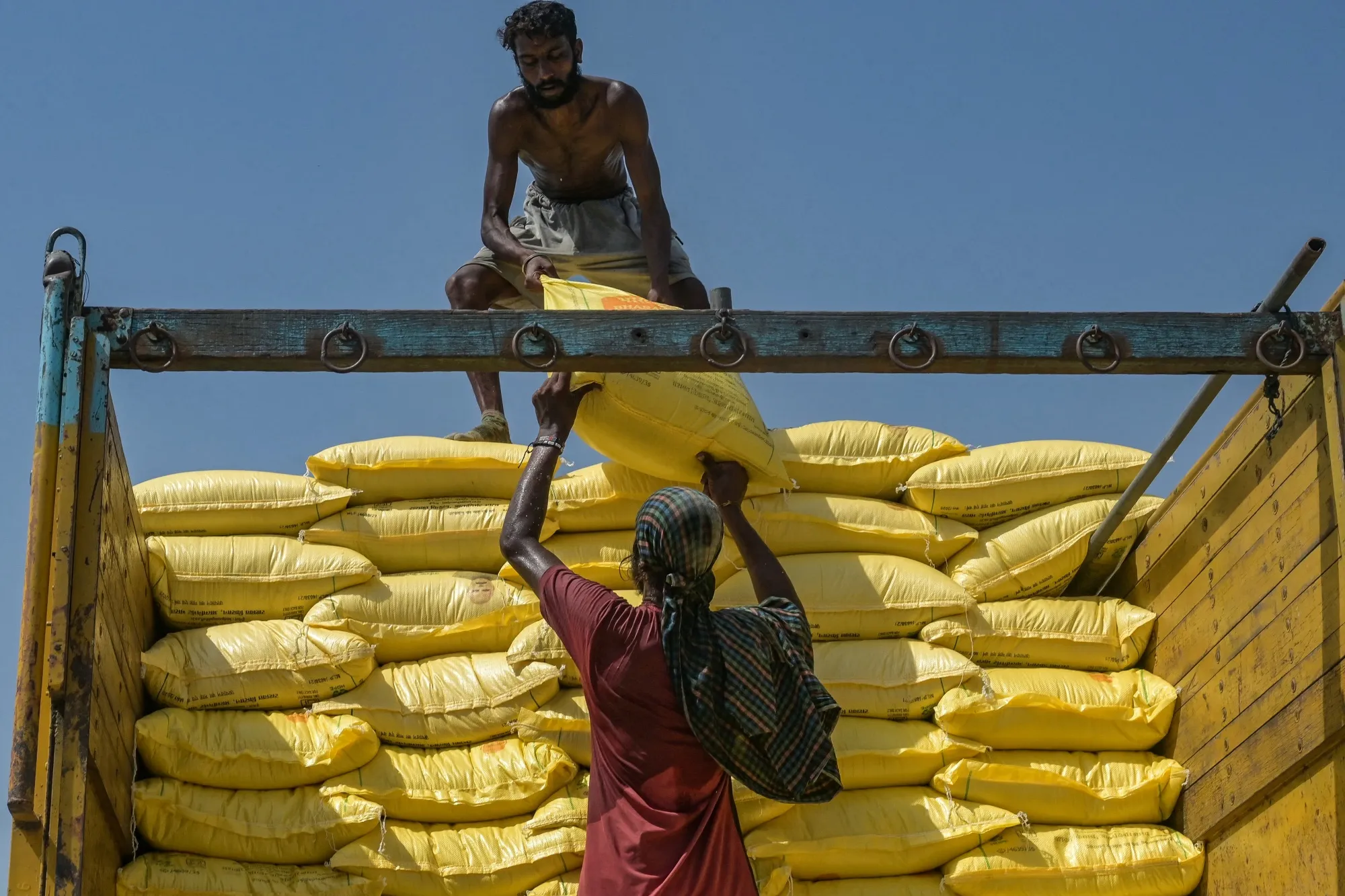 Workers load sacks of fertilizer onto a truck at a railway station in Amritsar, India.