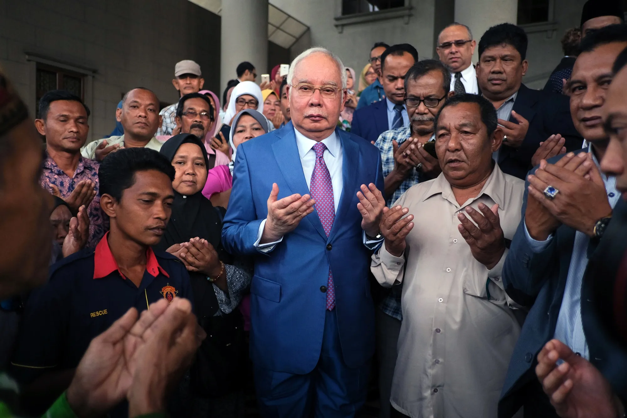 Najib Razak, center, offers prayers with his supporters at the Kuala Lumpur Courts Complex in Kuala Lumpur on Dec. 3.