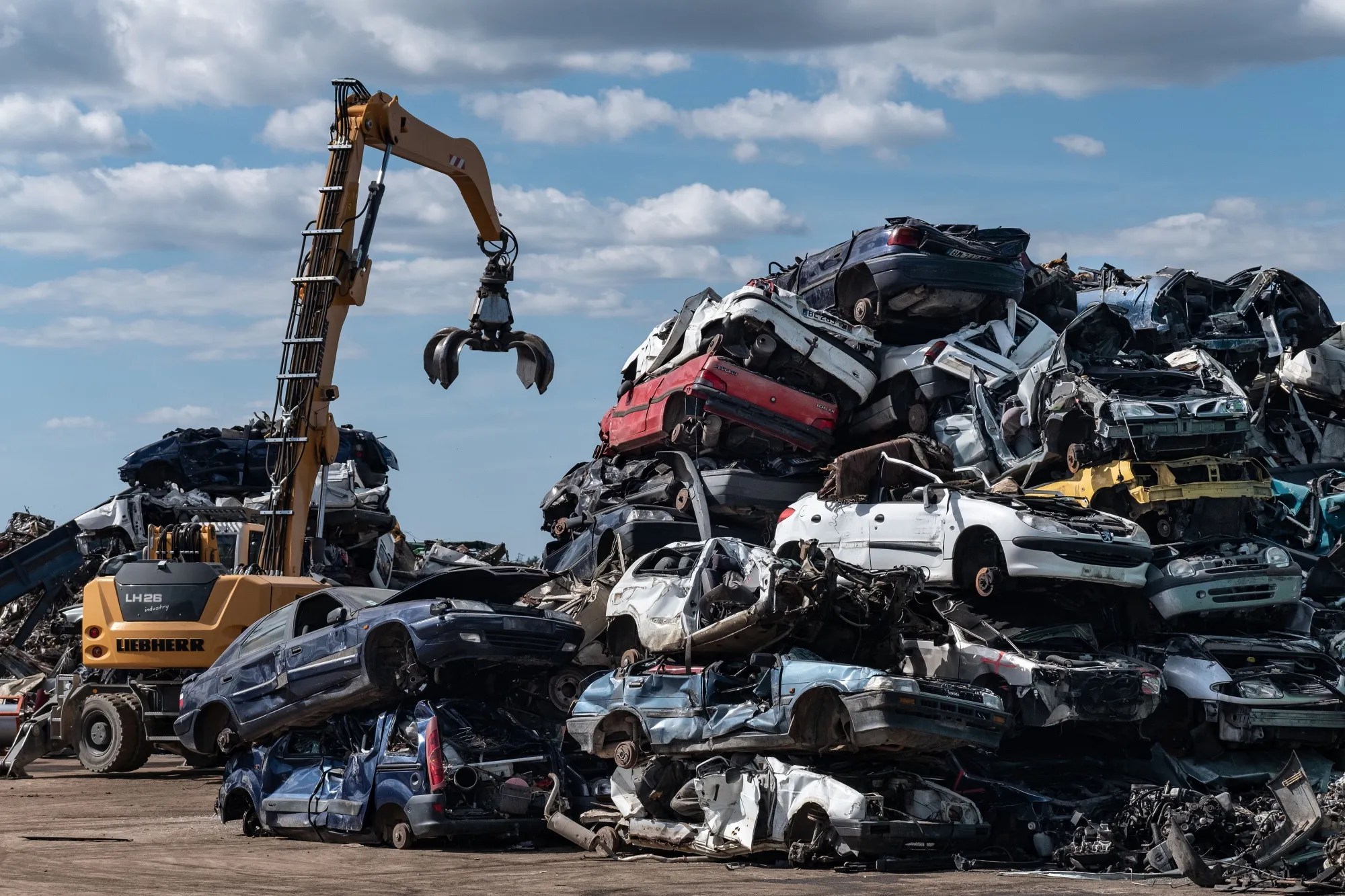 A claw crane beside piles of crushed cars at the Boudou Recycling scrapyard in Salles-La-Source, France.