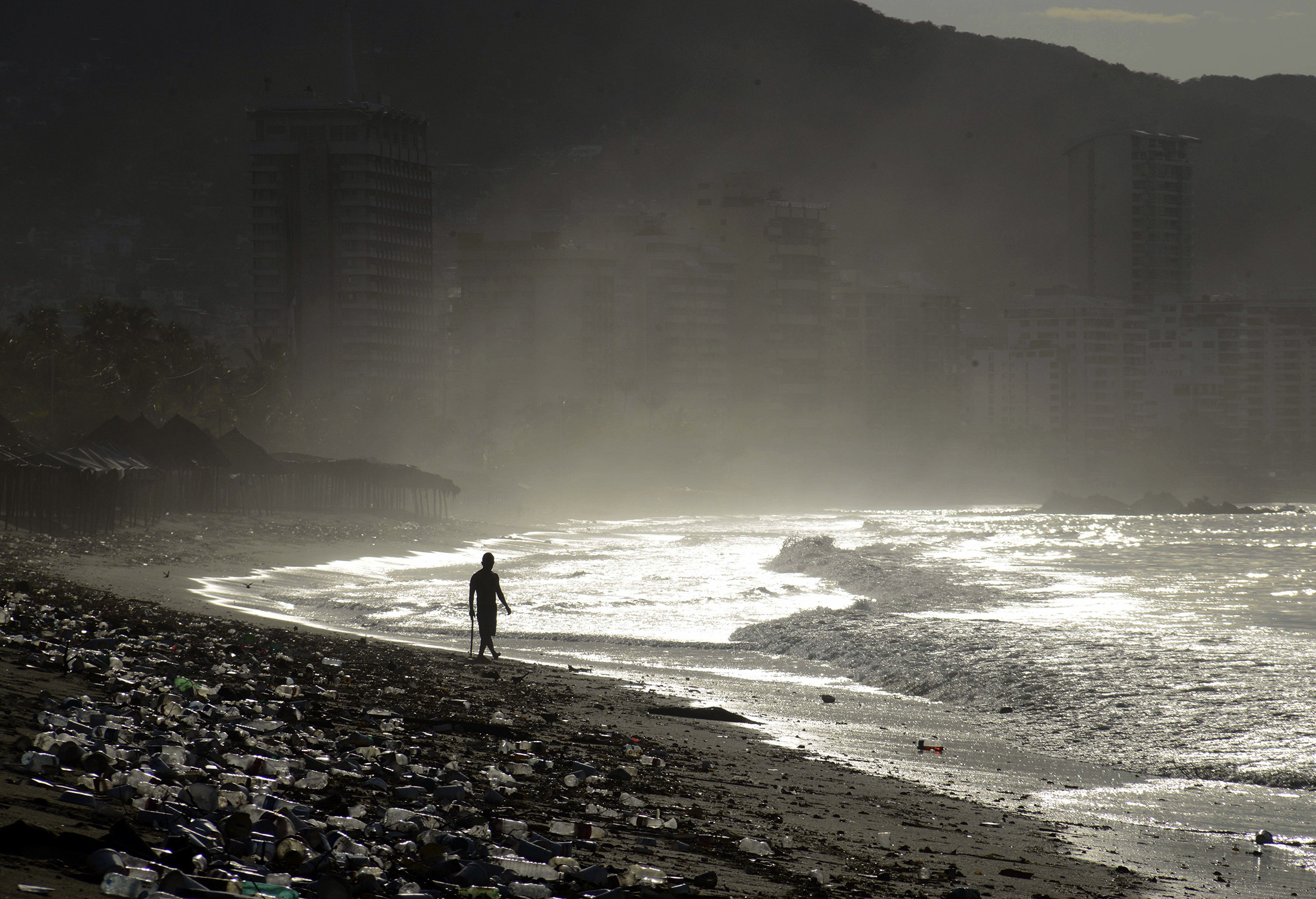 A person walks past waste at Santa Lucia beach in Acapulco, Guerrero state, Mexico on June 7.
