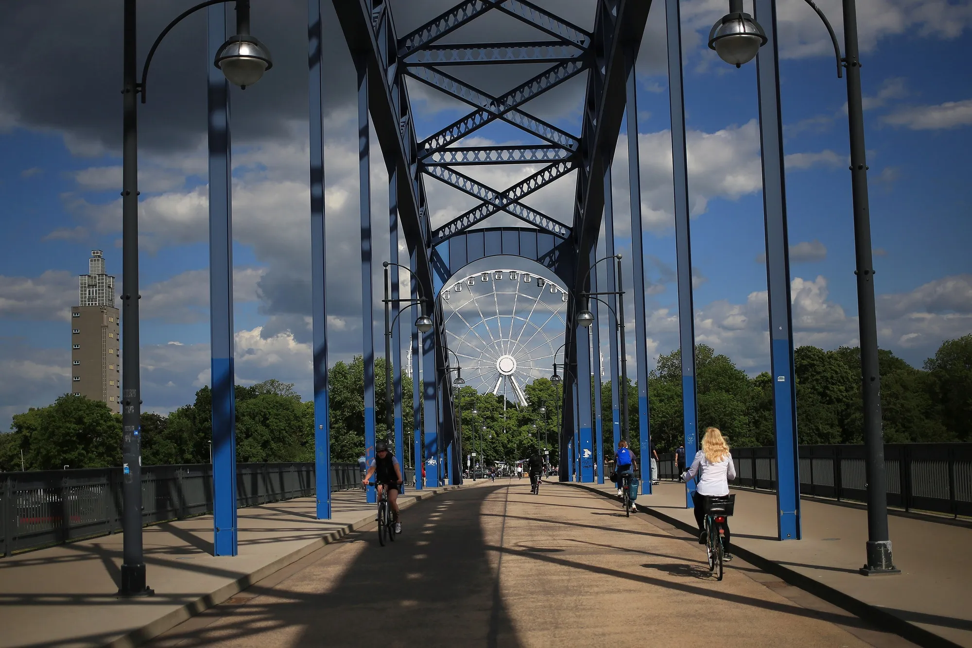 Pedestrians and cyclist cross Sternbruecke bridge near a ferris wheel in Magdeburg, Germany, on May 28.