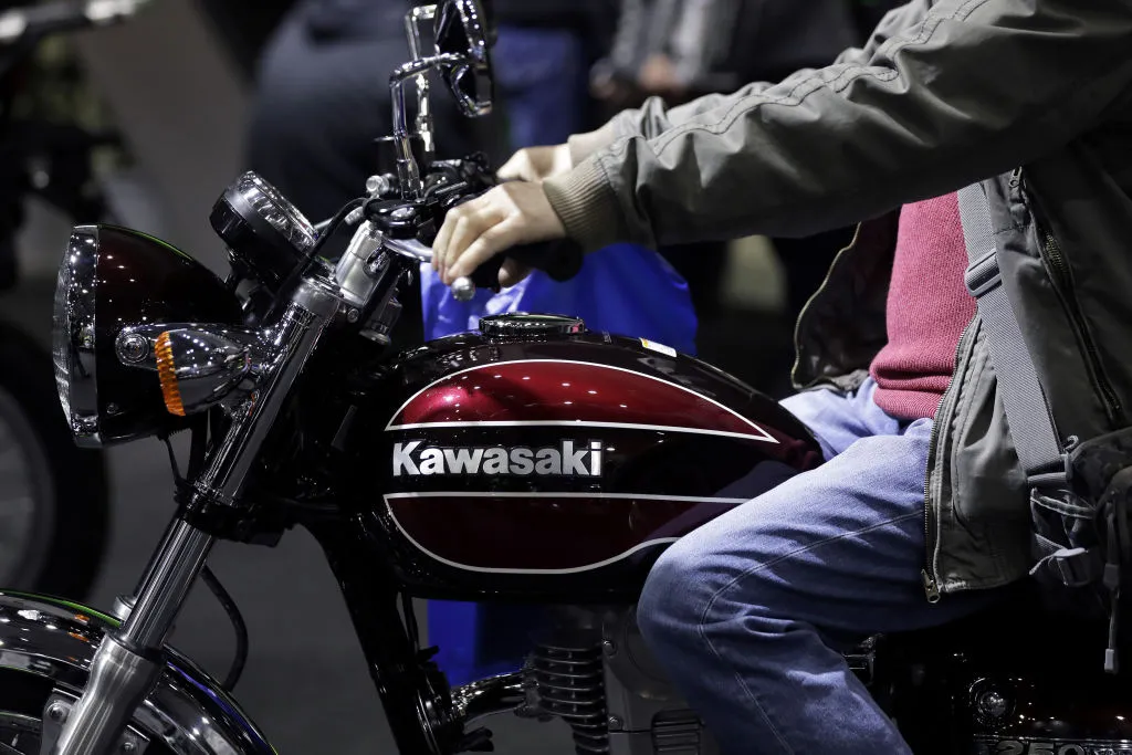 An attendee tries out a Kawasaki Heavy Industries Ltd. Estrella Final Edition motorcycle on display at the Tokyo Motorcycle Show in Tokyo.
