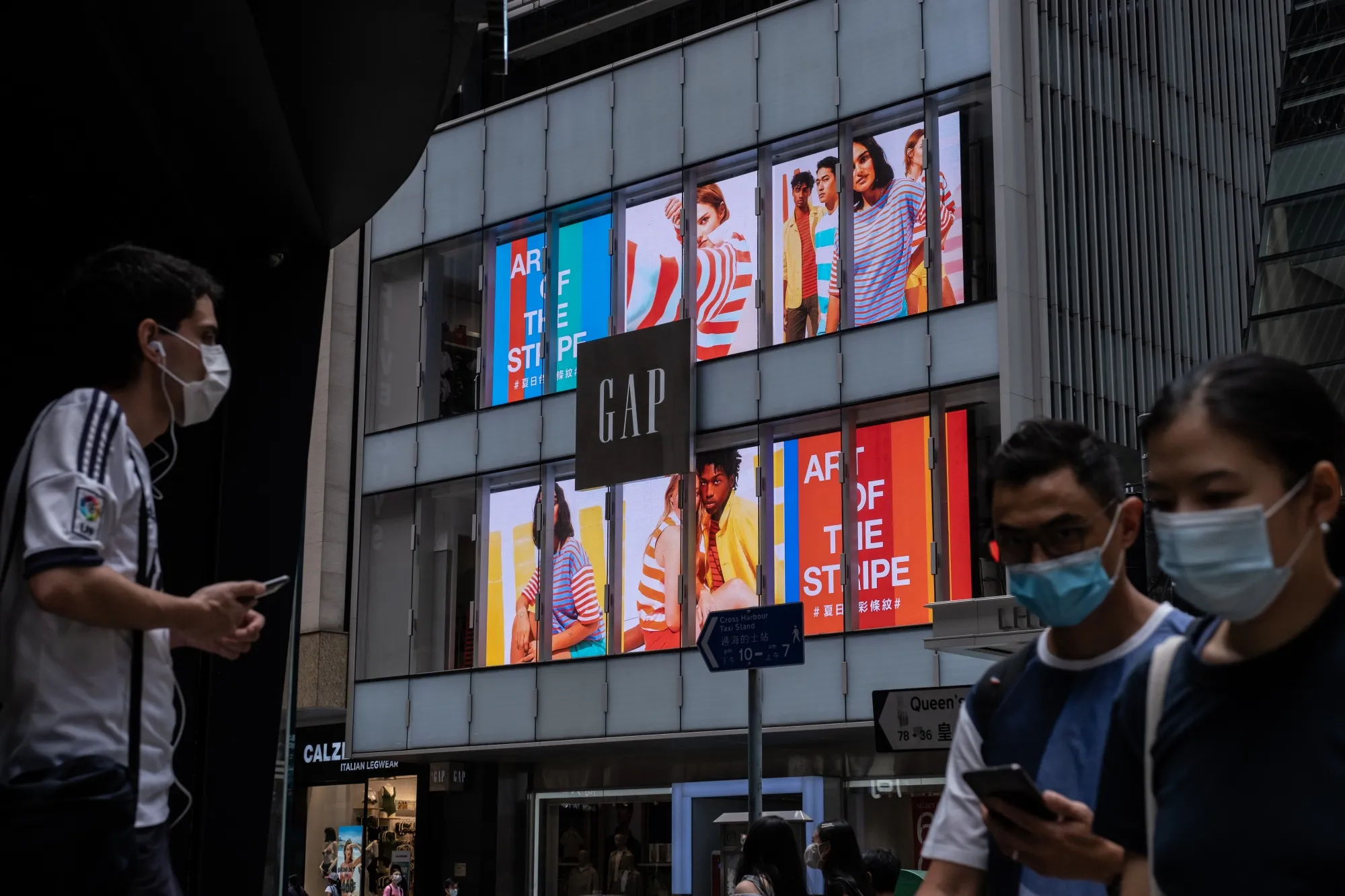 Pedestrians wearing protective masks walk past a Gap store in Hong Kong.