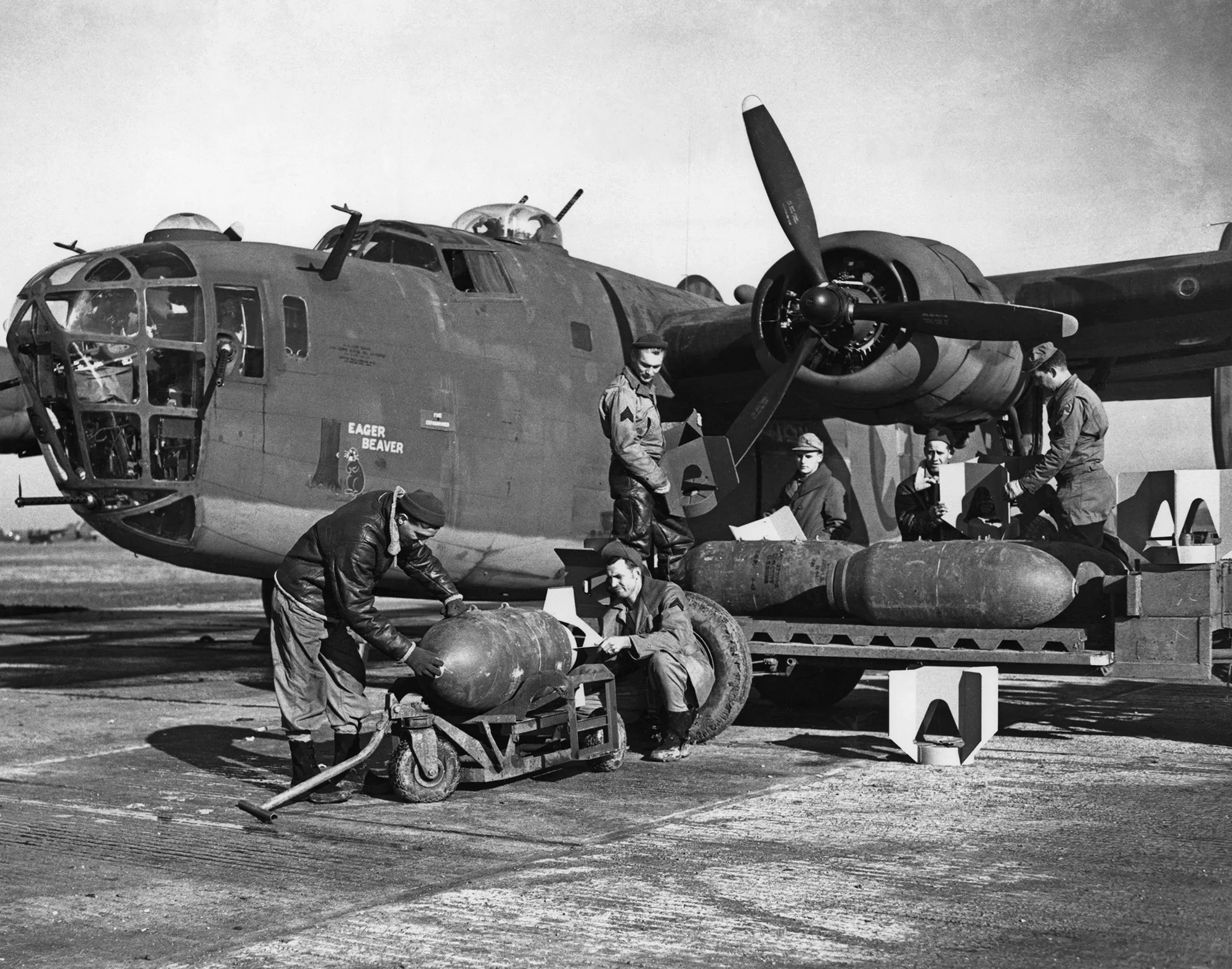 American ground crew priming and loading 1000-pound bombs into a B-24 Liberator bomber, 1943.&nbsp;