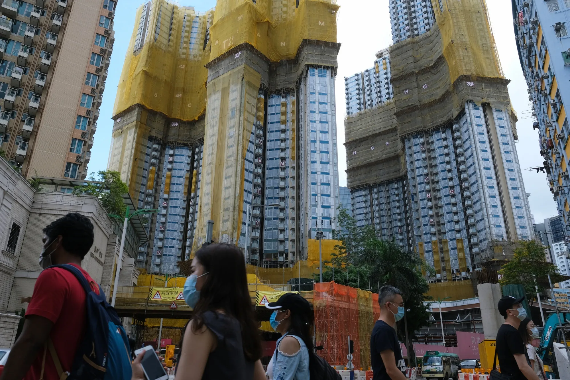 Pedestrians walk past a residential development in Hong Kong.