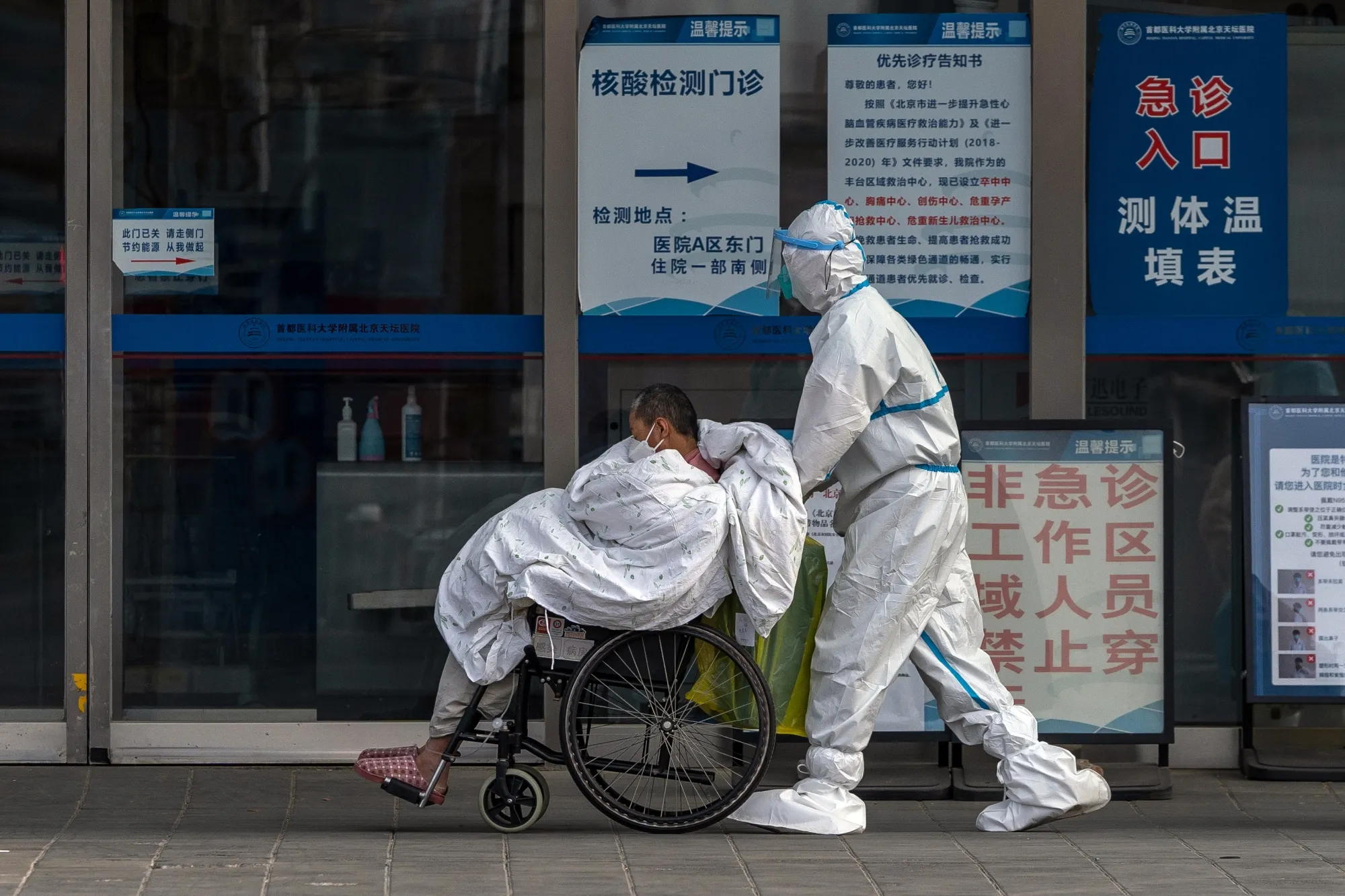 A health worker&nbsp;pushes a patient at a hospital in Beijing on Wednesday.