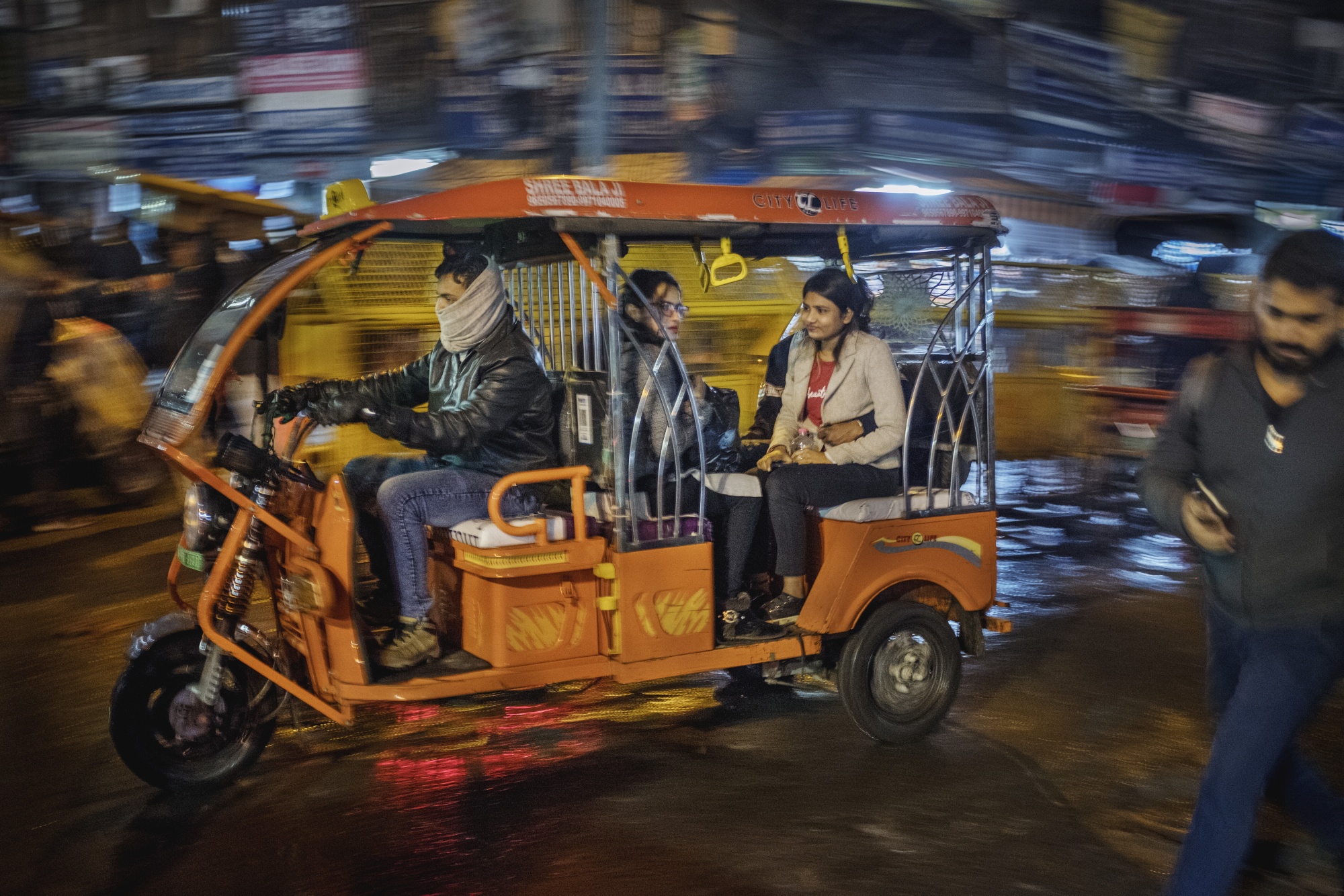 Passengers travel in an e-rickshaw in New Delhi.&nbsp;