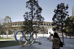A woman takes photographs of Olympic rings installed outside the Japan Olympic Museum near the New National Stadium, the main venue for the Tokyo 2020 Olympic and Paralympic Games, in Tokyo.
