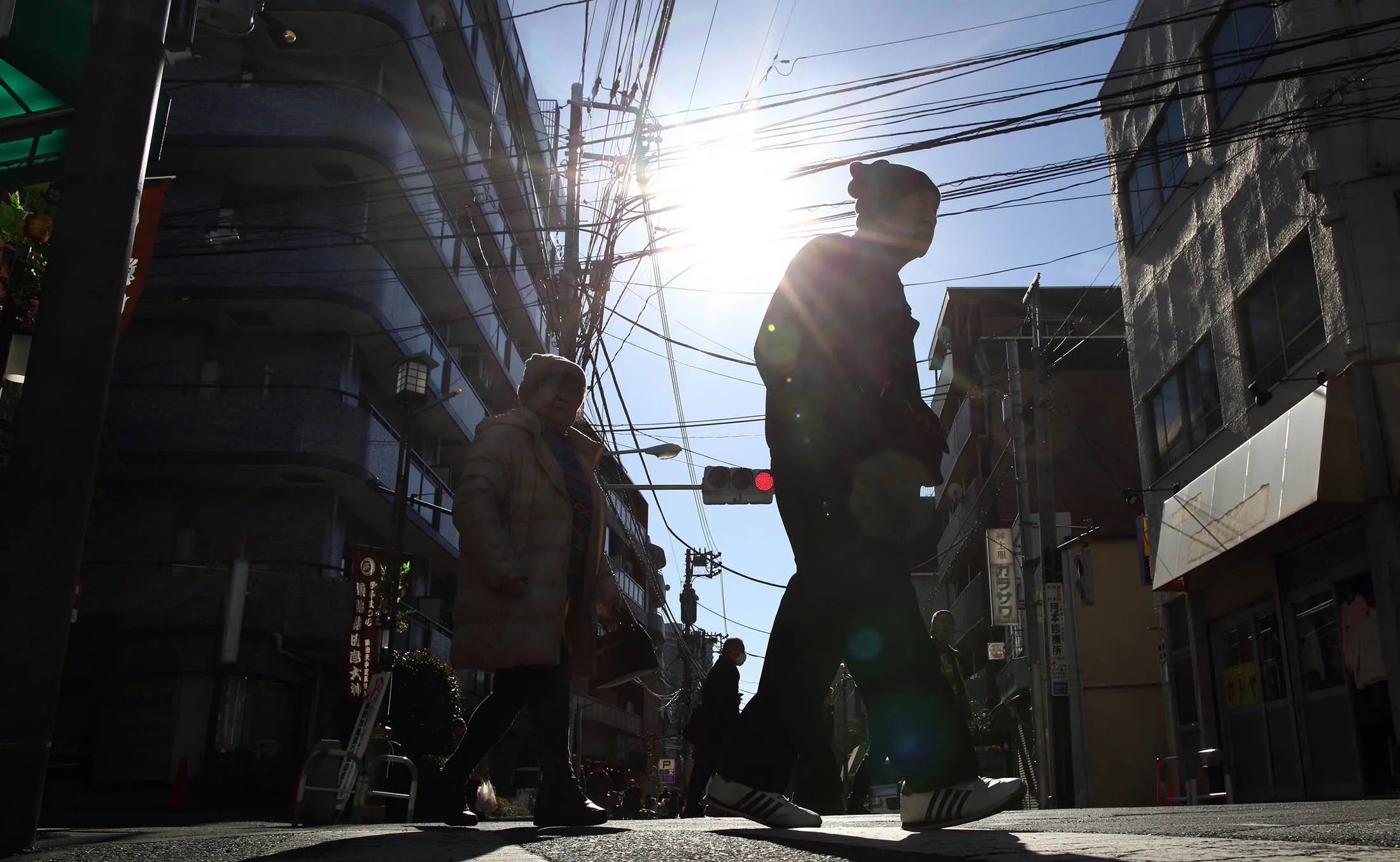 Pedestrians walk through the Sugamo Jizo-dori shopping area of Tokyo, Japan, on Tuesday, Jan. 13, 2015. Japan plans a record budget for next fiscal year to support an economy that fell into recession after Prime Minister Shinzo Abe's government increased the sales tax.
