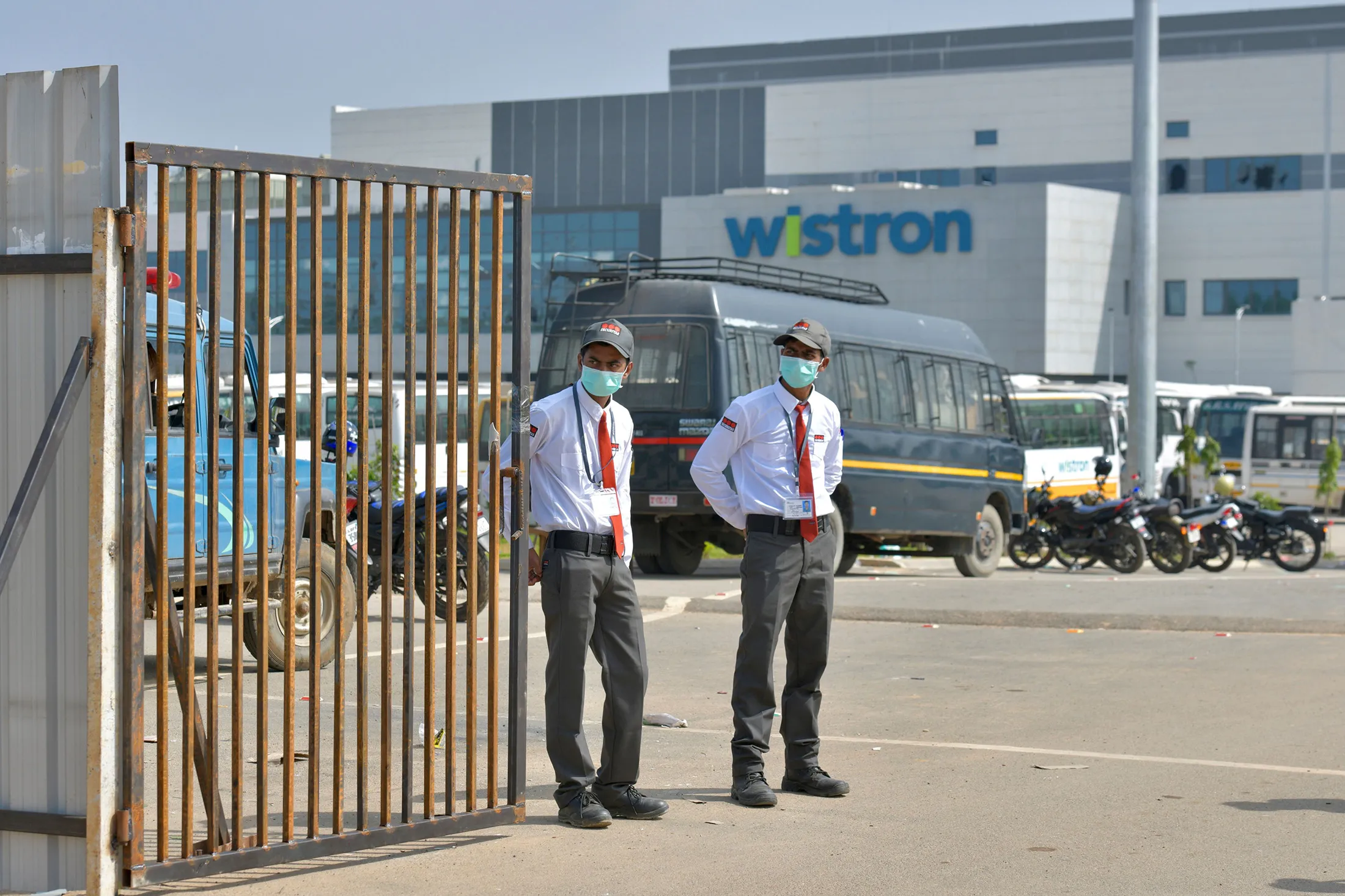Private security personnel guard the entrance of a Taiwanese-run iPhone factory at Narsapura, about 60 km from Bangalore on December 13, 2020. - Authorities vowed to crack down on workers who went on a violent rampage at a Taiwanese-run iPhone factory in southern India over allegations of unpaid wages and exploitation, with 100 people arrested so far. (Photo by Manjunath Kiran / AFP) (Photo by MANJUNATH KIRAN/AFP via Getty Images)