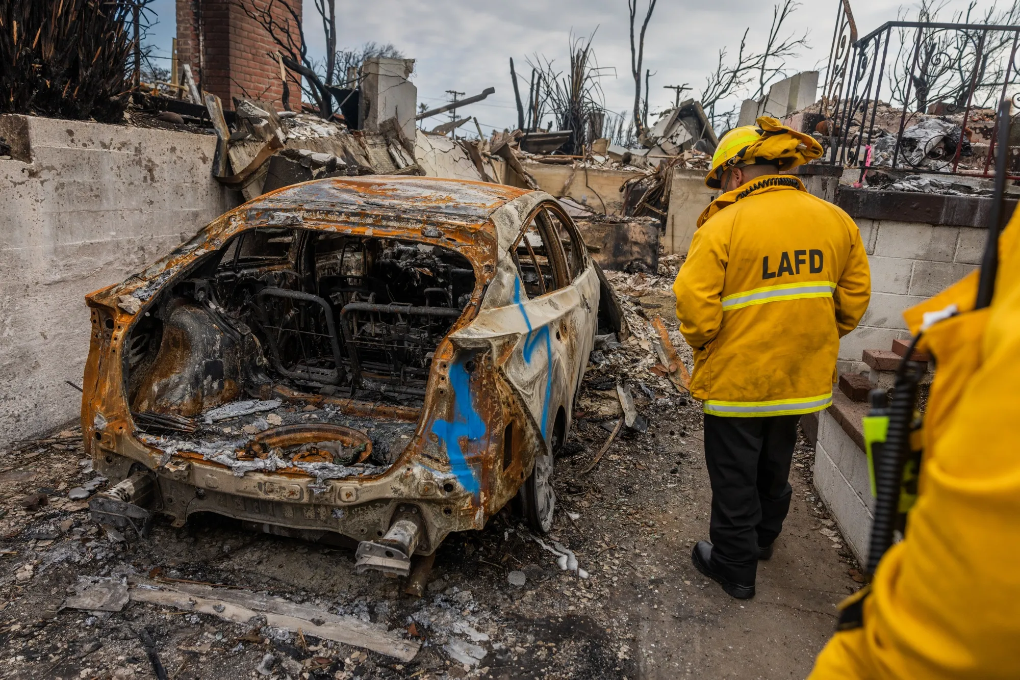Los Angeles Fire Department workers inspect a burned vehicle after the Palisades Fire on Jan. 30.
